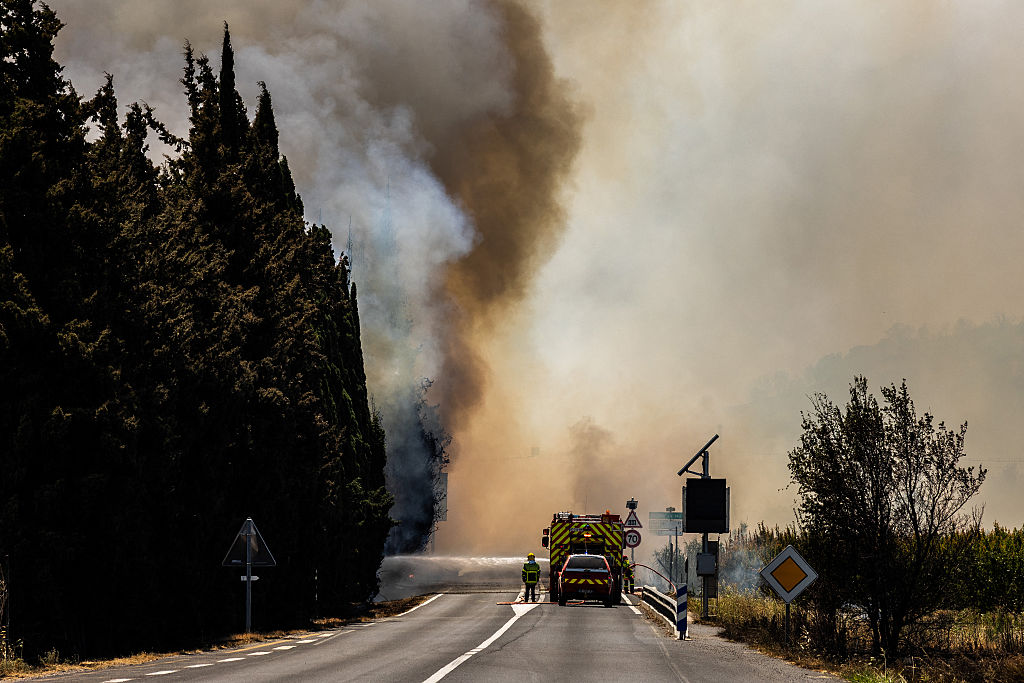A firefighter sprays water on flames as a wildfire rages in the southern France department of Pyrenees-Orientales near the town of Bouleternere