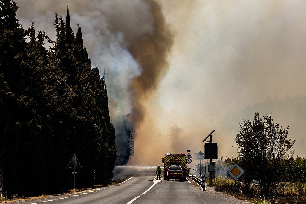 A firefighter sprays water on flames as a wildfire rages in the southern France department of Pyrenees-Orientales near the town of Bouleternere