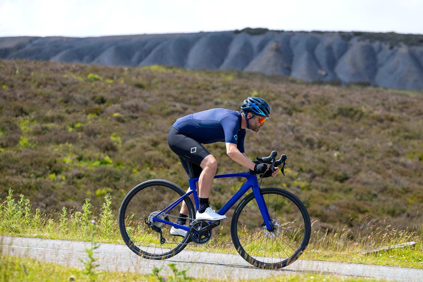 Male cyclist in blue top riding the Specialized Roubaix SL8 Sport 105 road bike