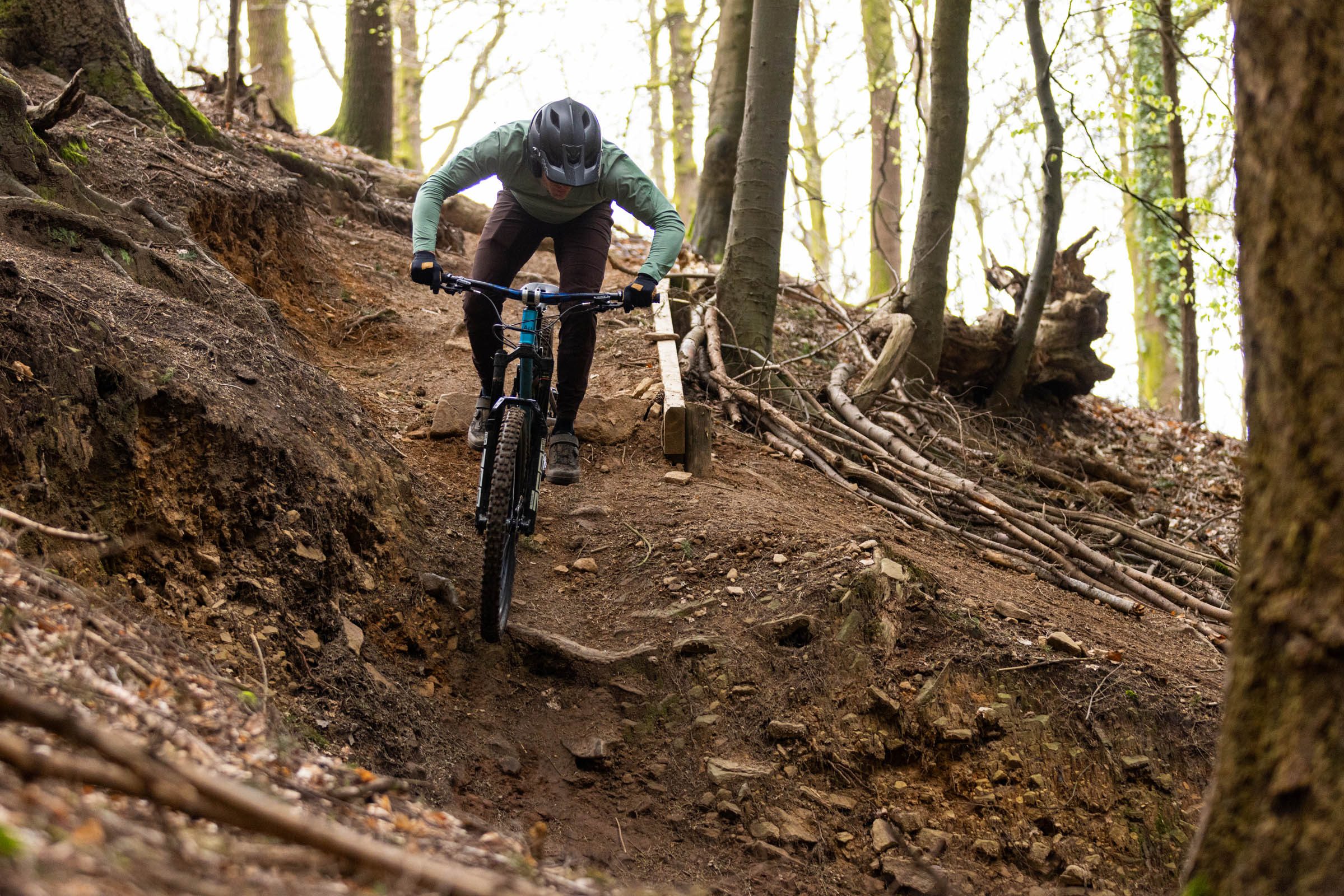 Rider on the Auckland Cycle Works Marra descending a steep, rocky woodland mountain bike trail