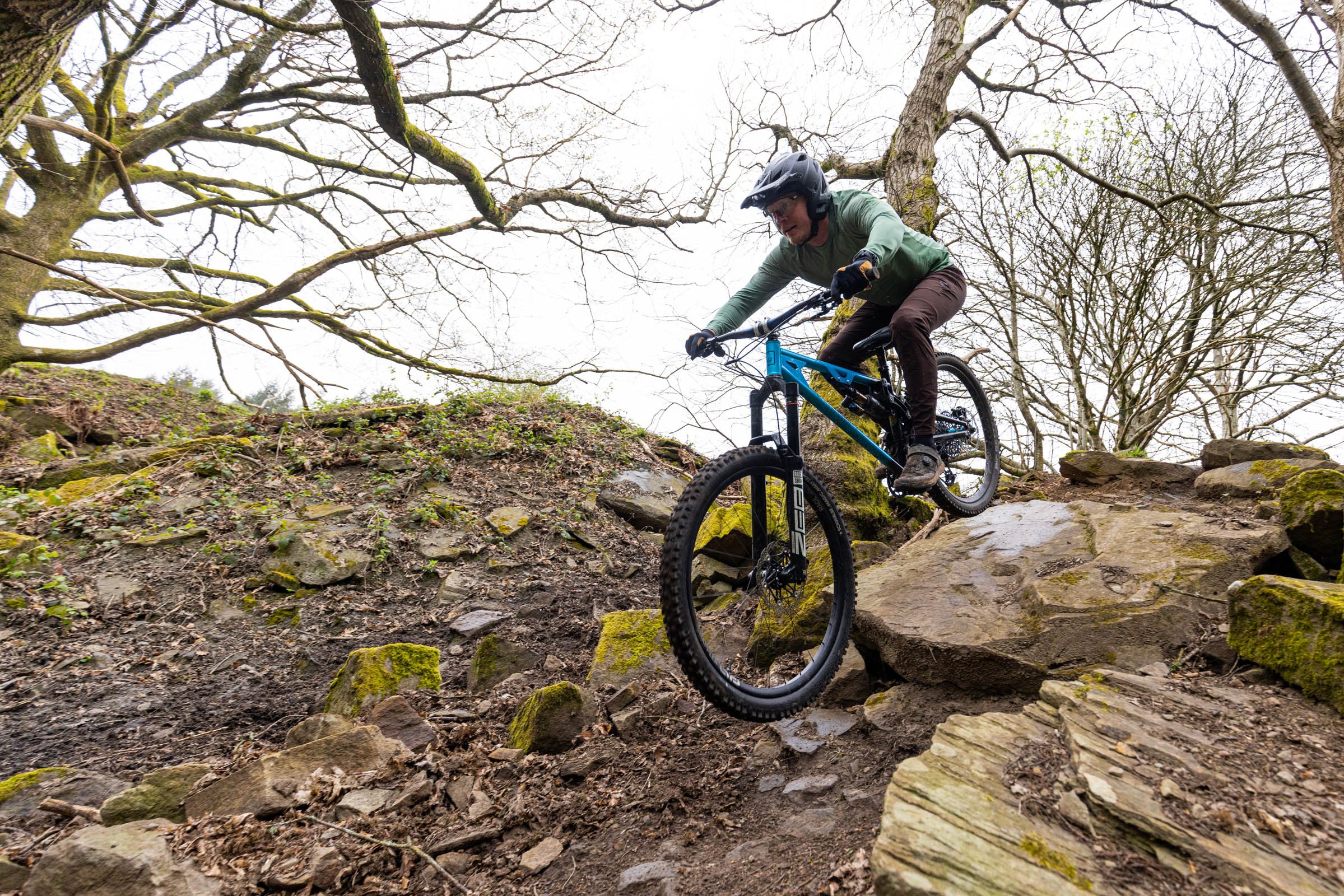 Rider on the Auckland Cycle Works Marra descending a rocky woodland mountain bike trail