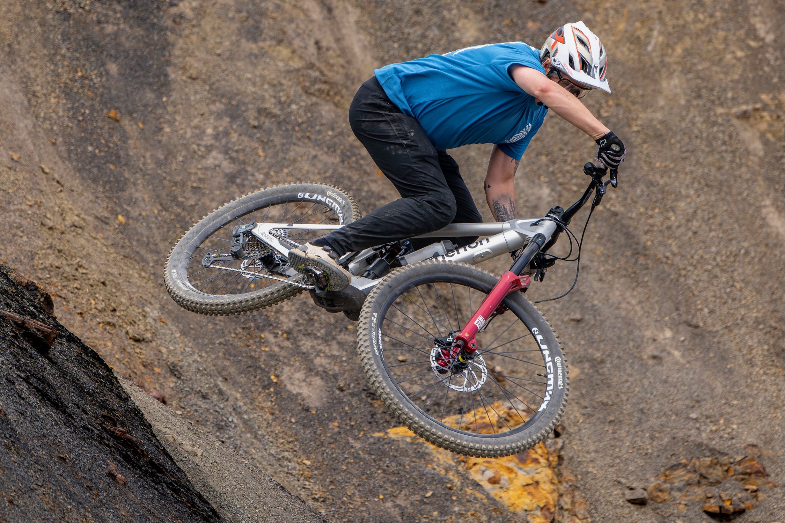 Rider jumps the silver Atherton S.170E.2 from a steep rocky lip on a mountain-bike trail