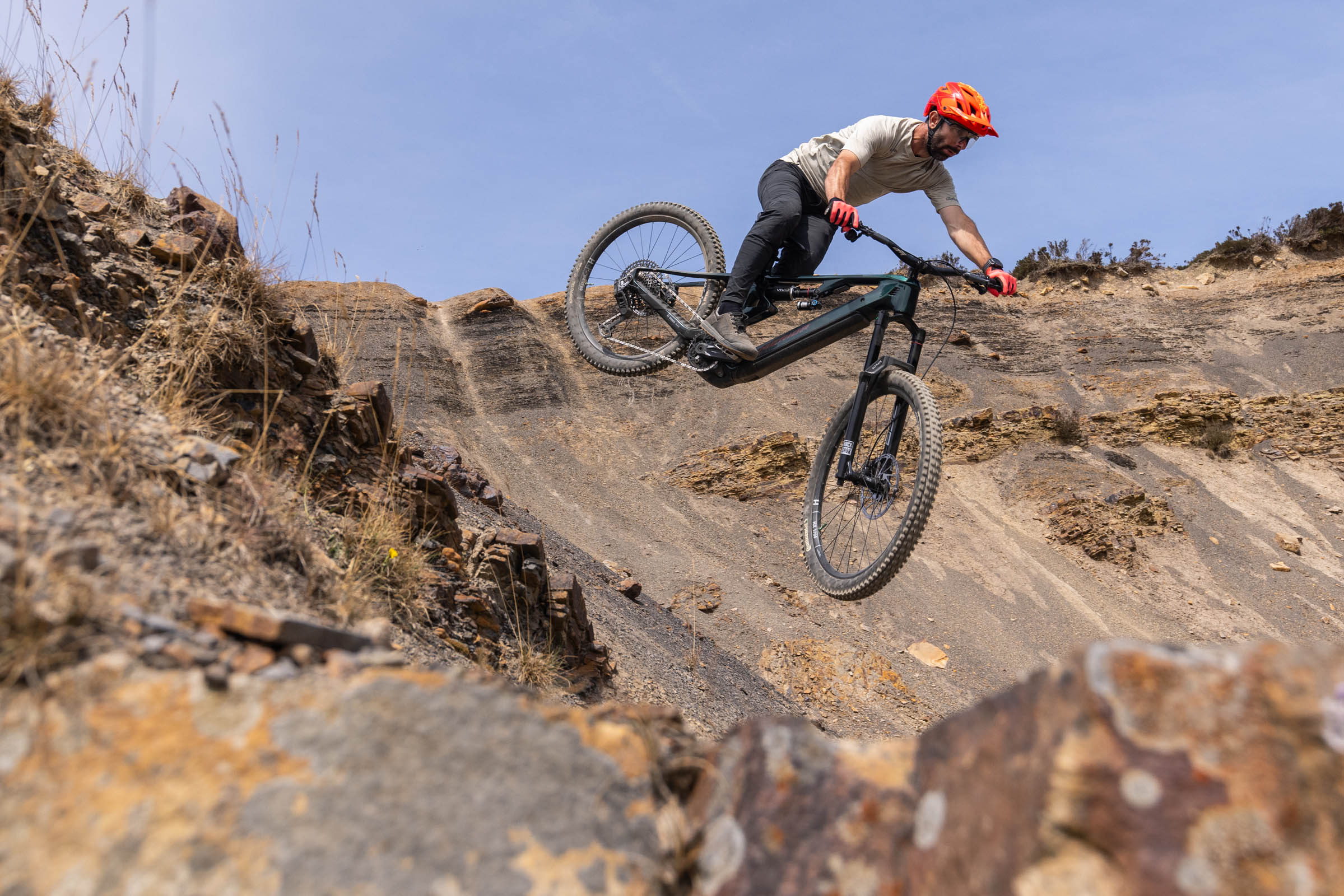 Rider jumps the dark green Merida Lithos 8000 across a steep, rocky mountain-bike trail