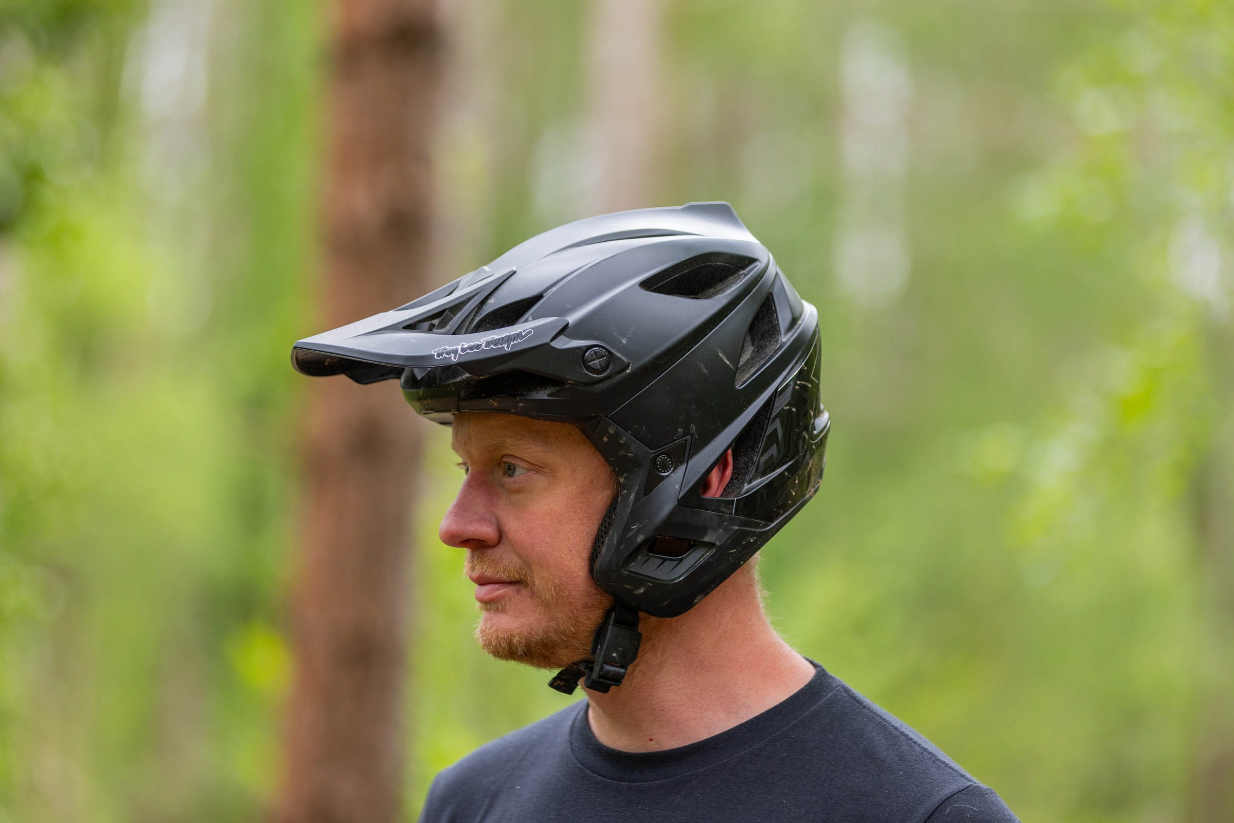 Rider wearing a black Troy Lee Designs Stage Stunt 3/4-coverage mountain bike helmet in woodland.