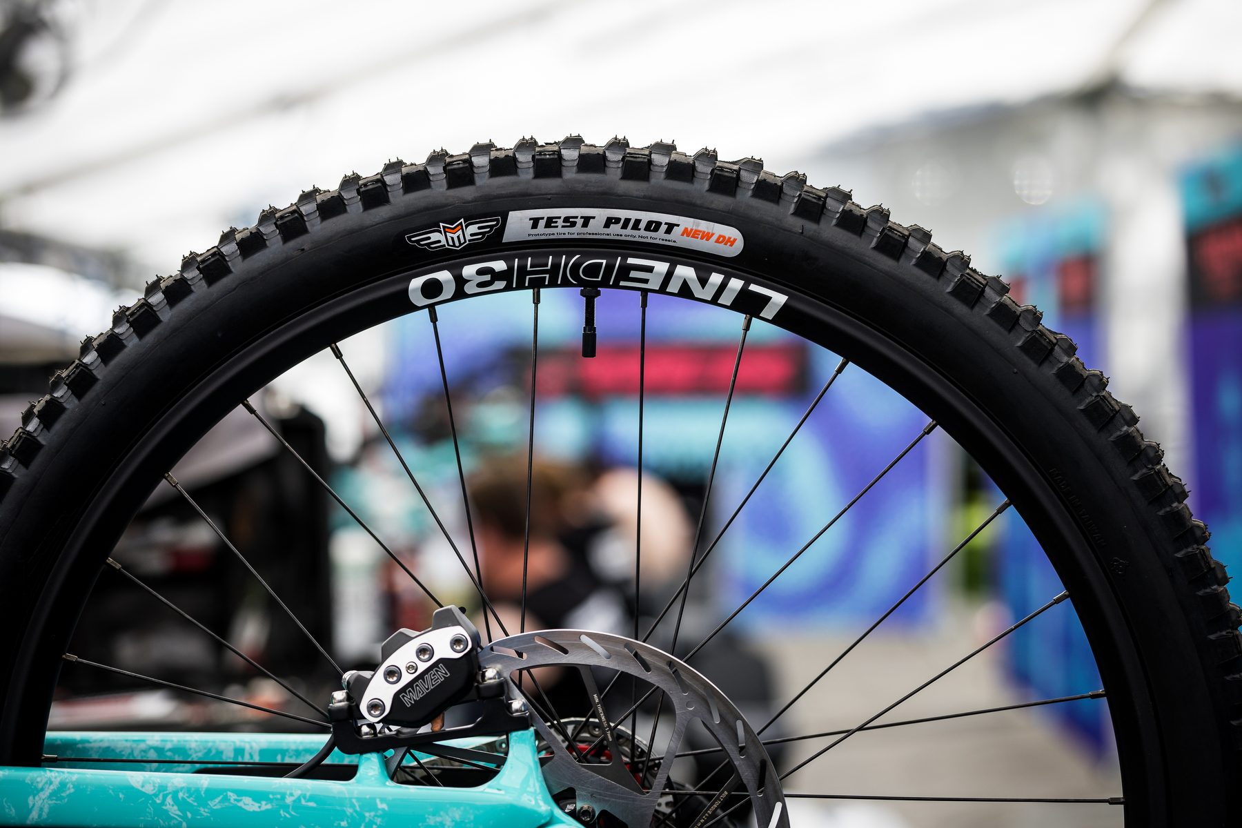 Maxxis downhill tyre marked Test Pilot New DH fitted to a Line DH30 wheel on a race bike.