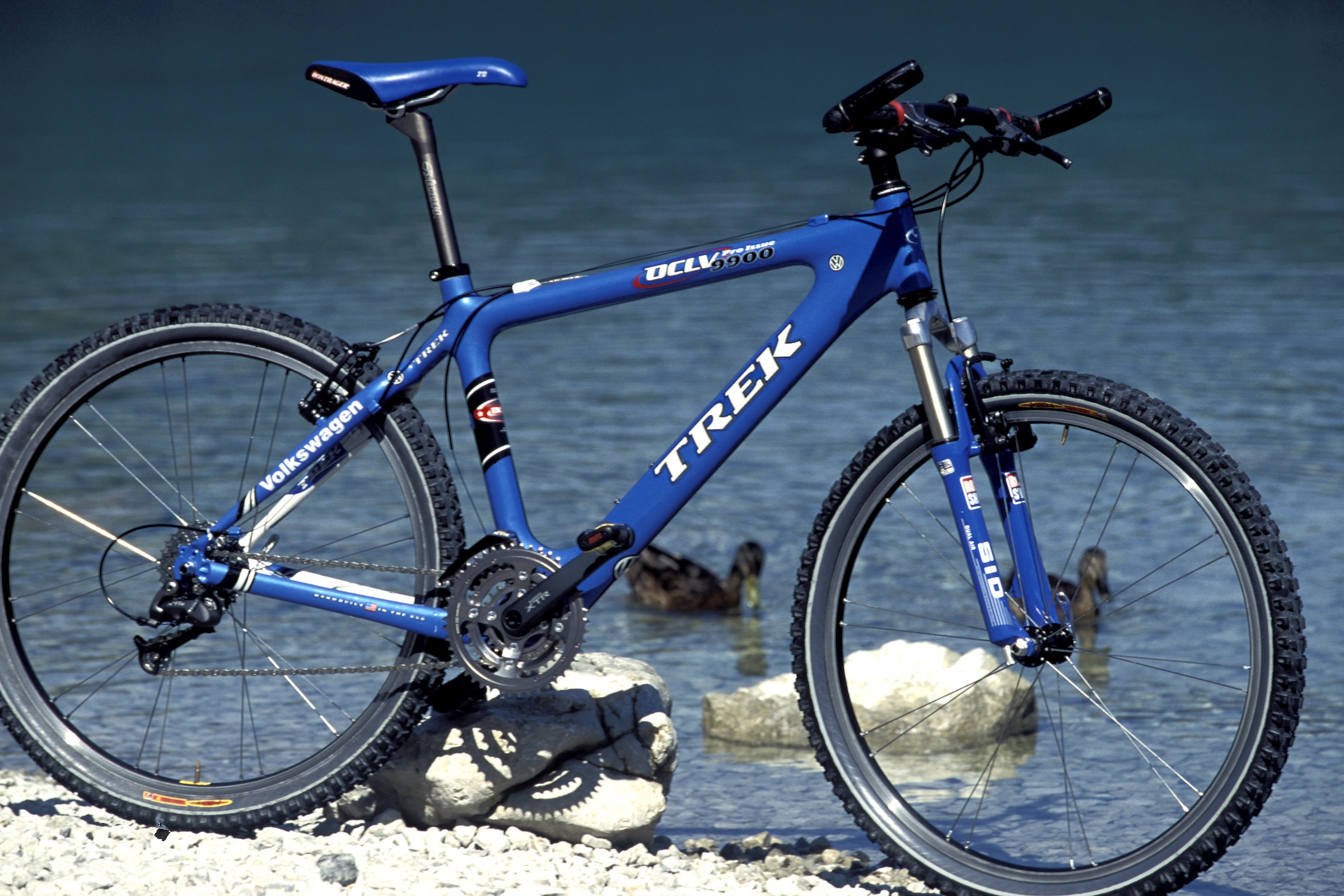 Blue Trek OCLV 9900 hardtail mountain bike photographed beside clear water.
