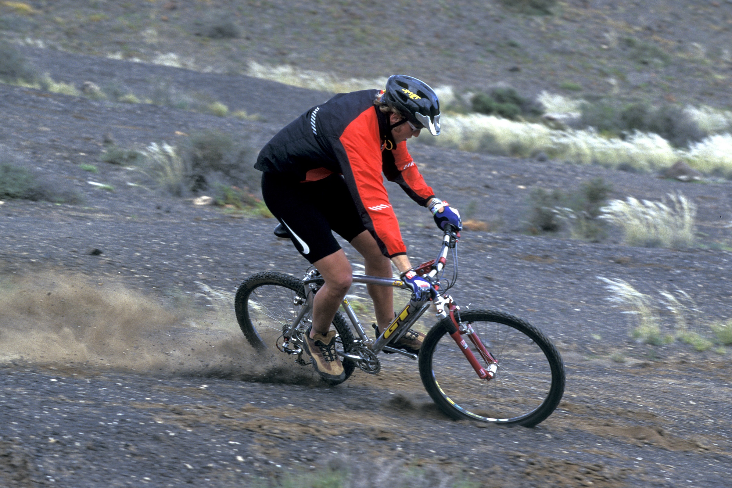 Steve Peat cornering on a GT LTS full-suspension mountain bike on a dusty trail.