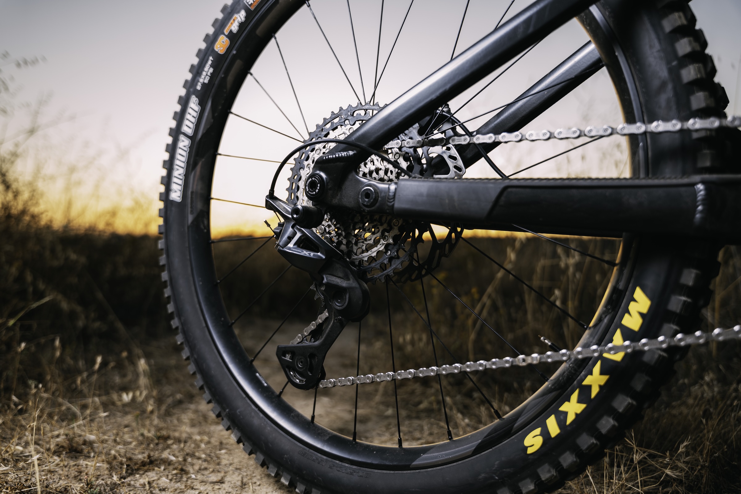 Close-up of a Shimano Deore XT M8200 rear derailleur and cassette fitted to a mountain bike at sunset.