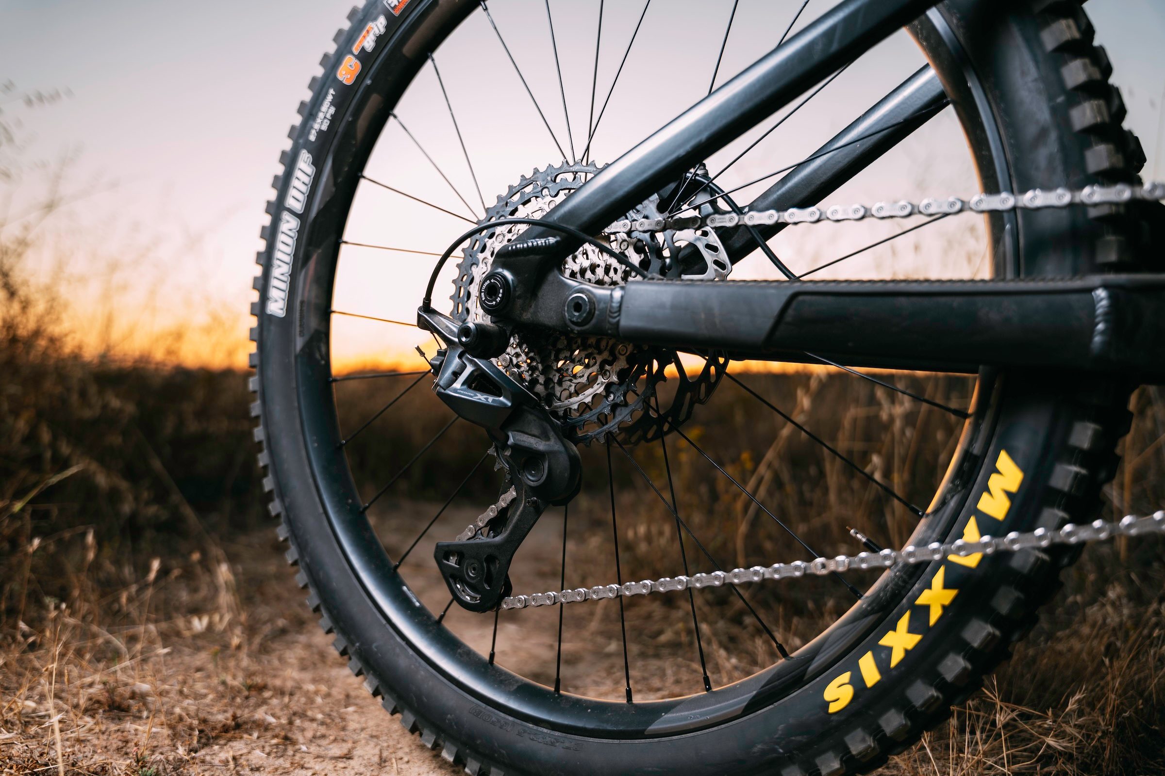 Close-up of a Shimano Deore XT M8200 rear derailleur and cassette fitted to a mountain bike at sunset.