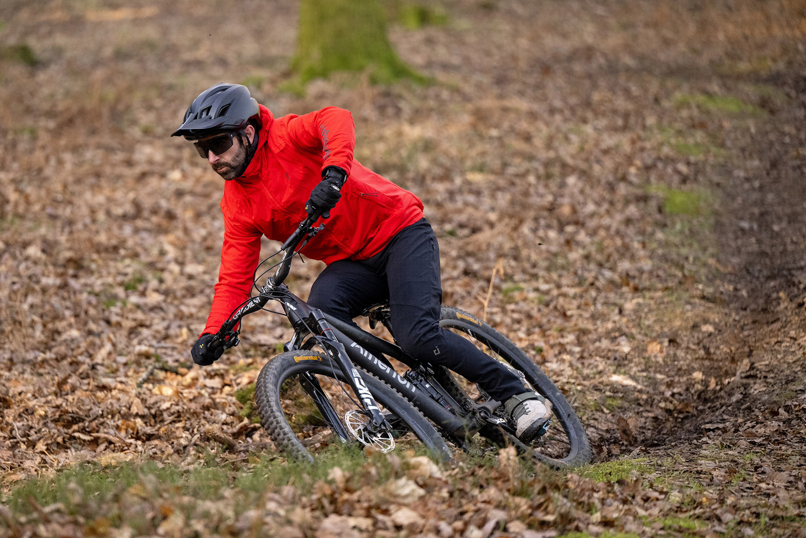 Male rider in red top riding the Atherton AM.130.1 full suspension mountain bike through woodland