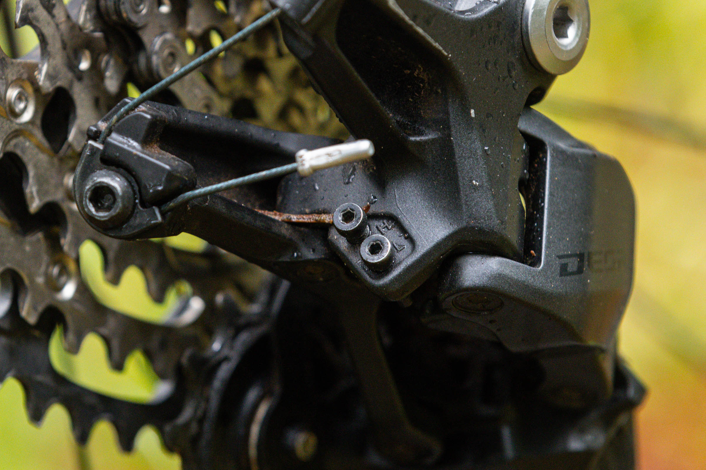 Close-up of the cable clamp and adjustment screws on a Shimano Deore M7200 rear derailleur.