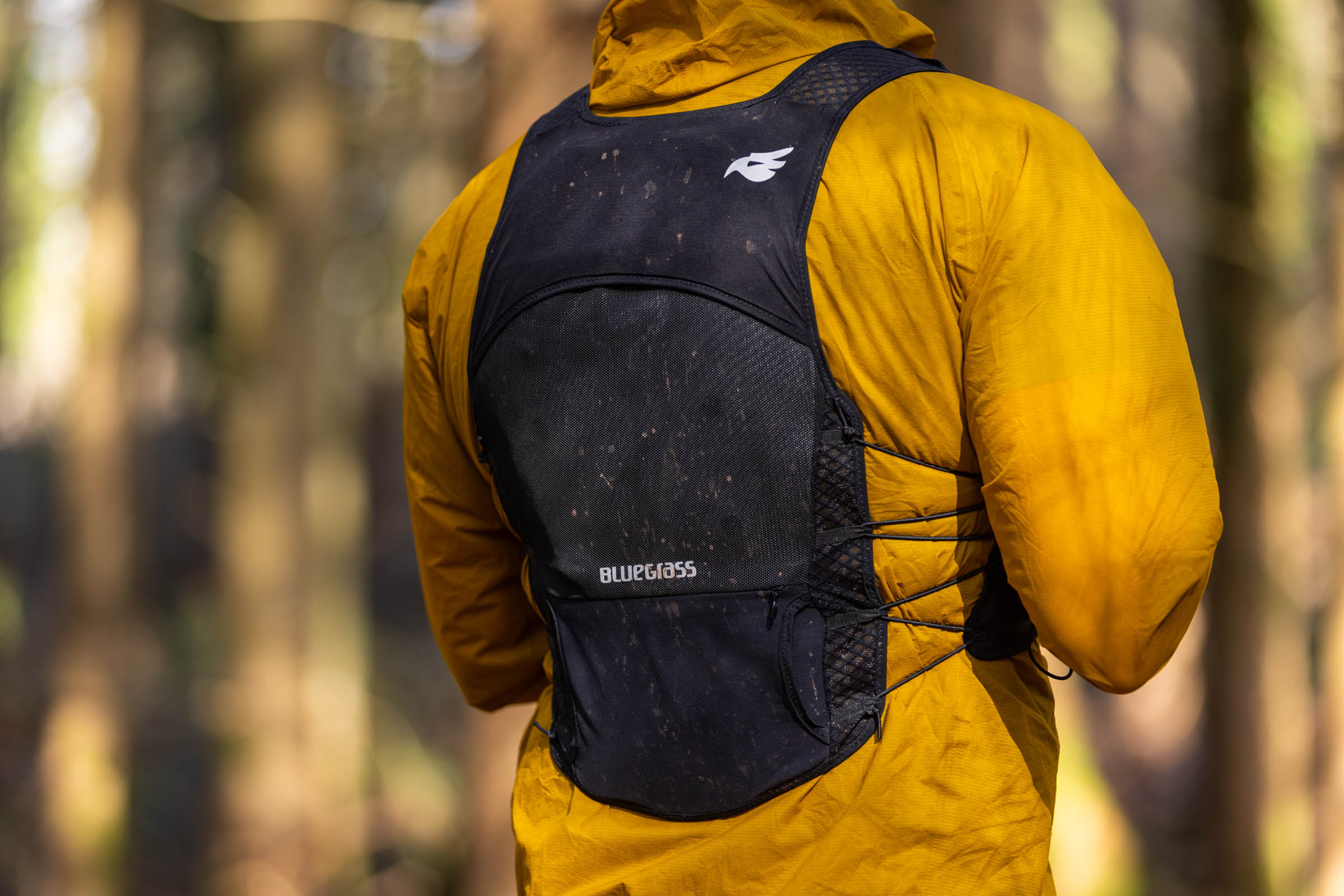 Rear three-quarter view of a rider wearing the Bluegrass Venture Vest over a yellow jacket, showing the back panel.