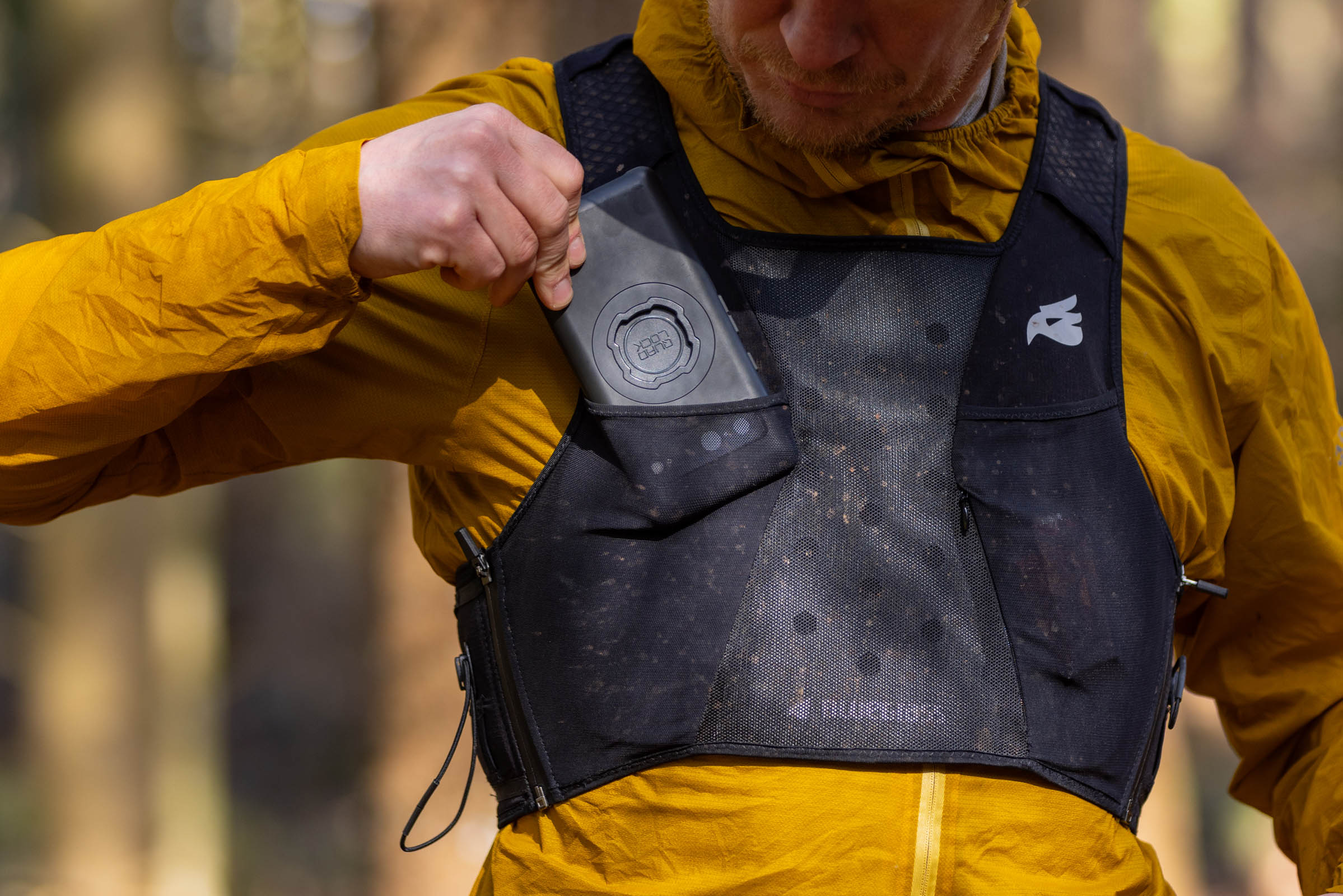 Rider pulling open a front storage pocket on the black Bluegrass Venture Vest.