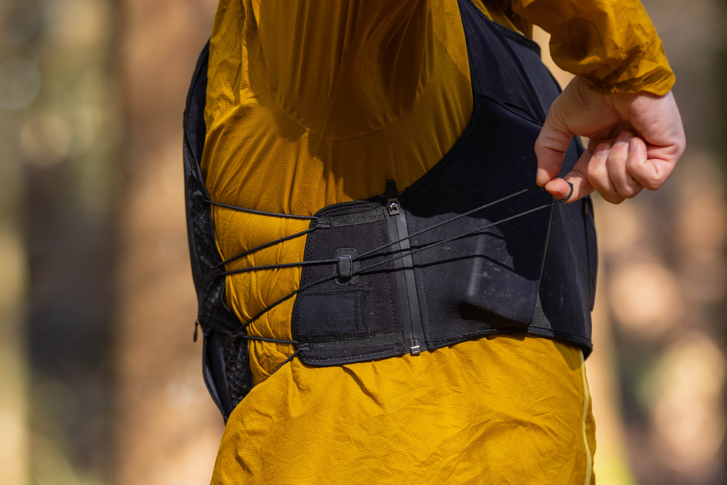 Close-up of a rider pulling an elastic adjustment cord on the side of the Bluegrass Venture Vest.