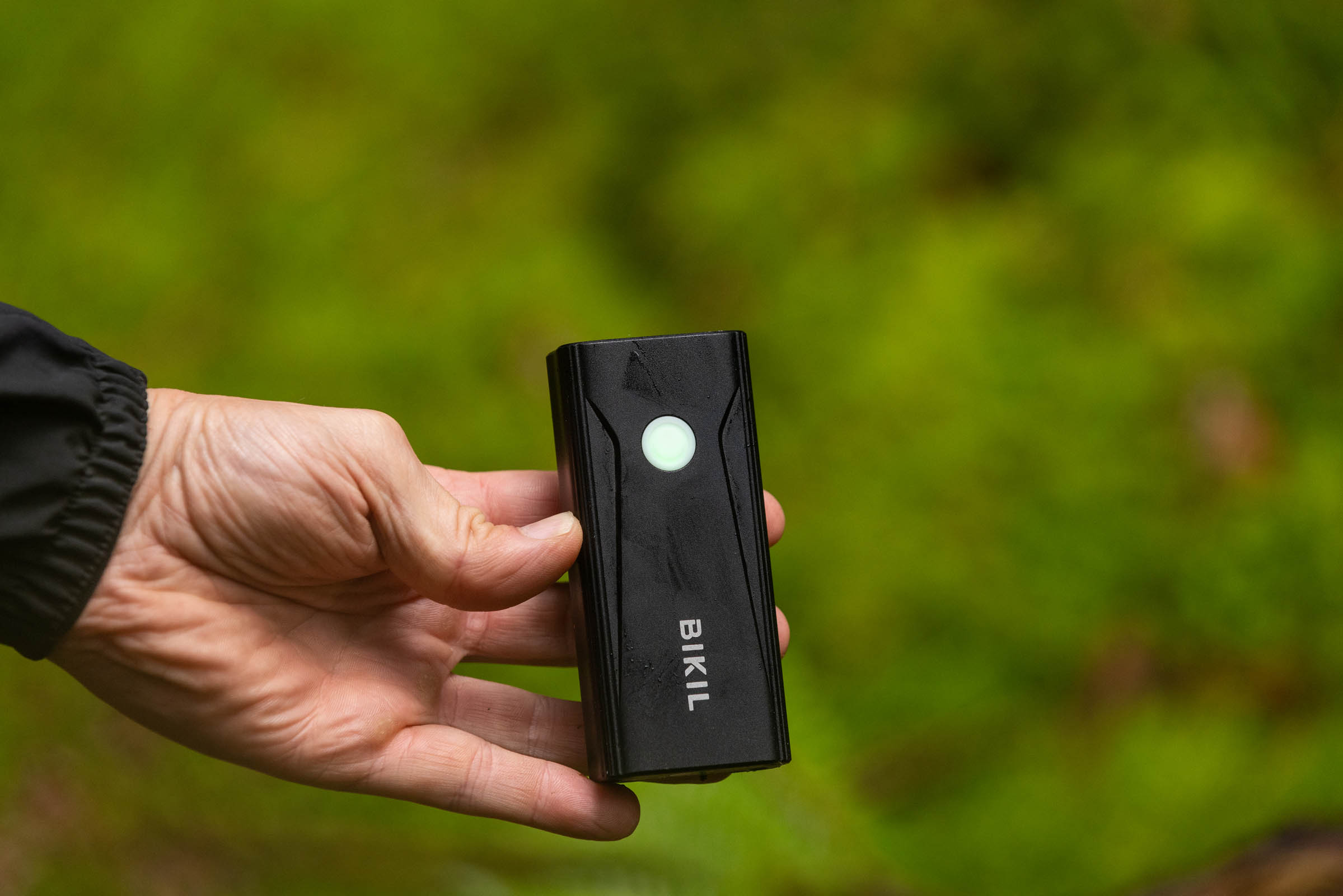 Bikil 2400 front light held in a hand with its illuminated top-mounted control button visible.