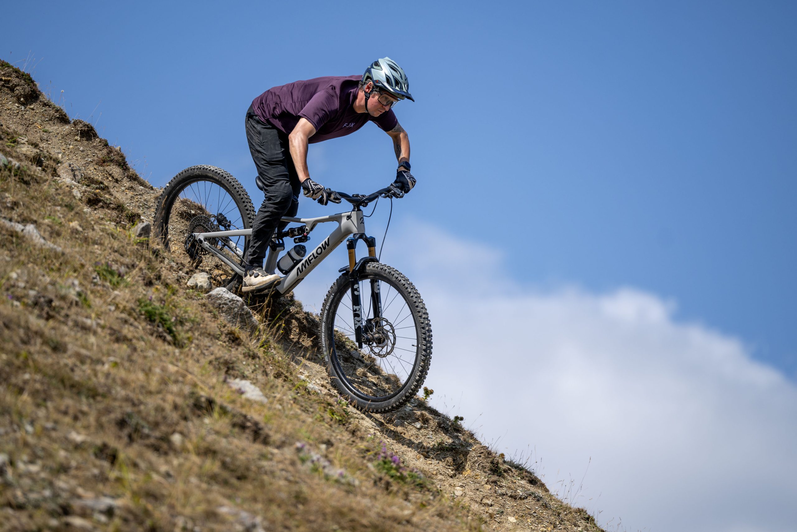 Rider descending a steep loose slope on a white Amflow PX Carbon Pro electric mountain bike