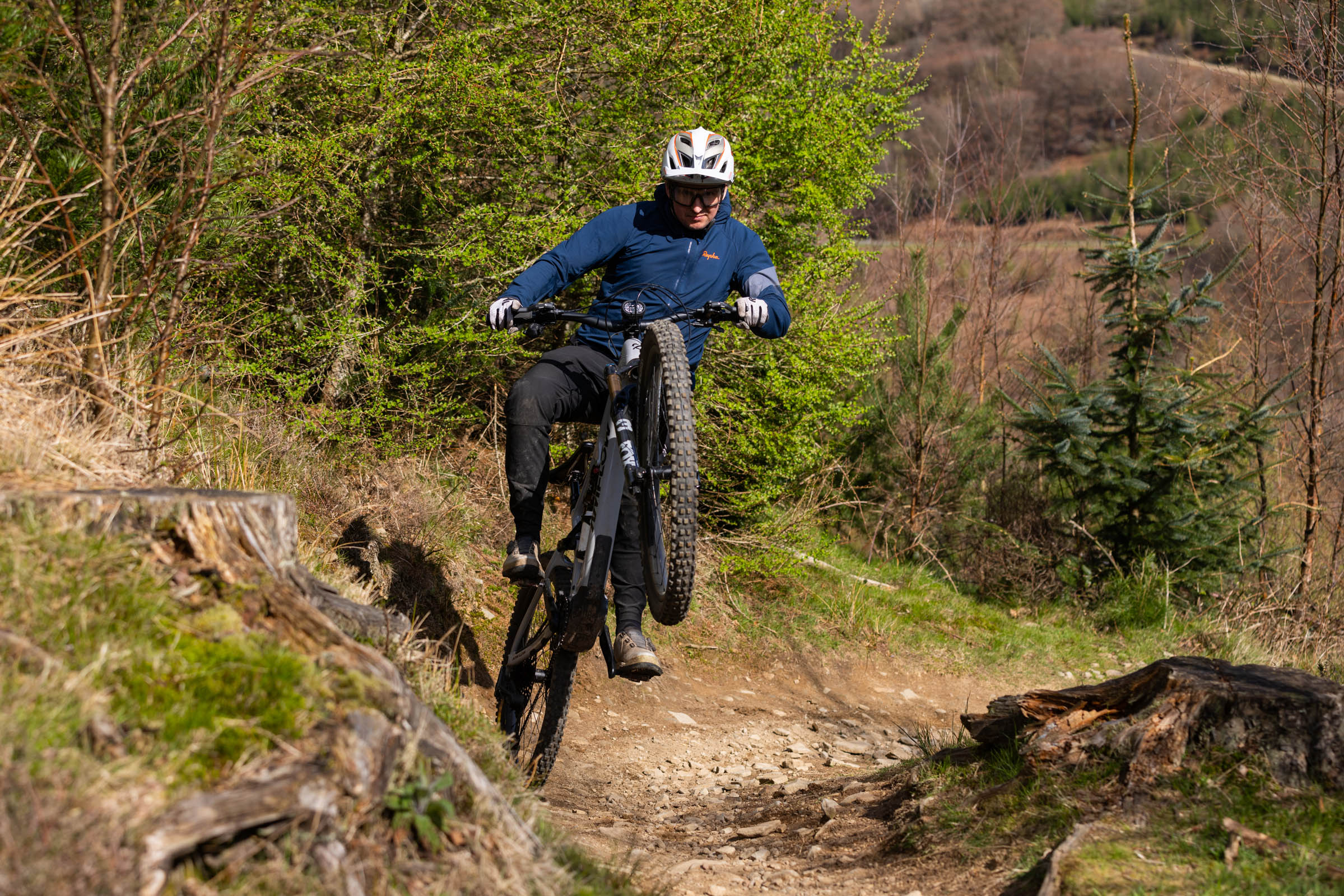 Rider lifting front wheel on a steep technical trail on an e-mountain bike