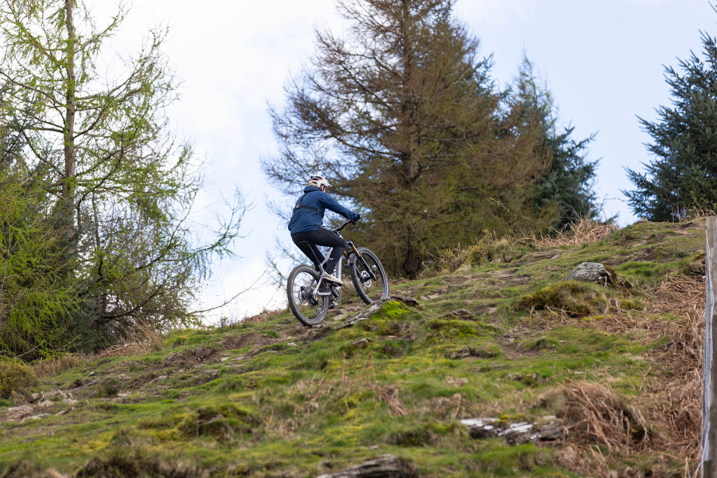 Rider climbing a steep grassy and rocky hillside on an e-mountain bike