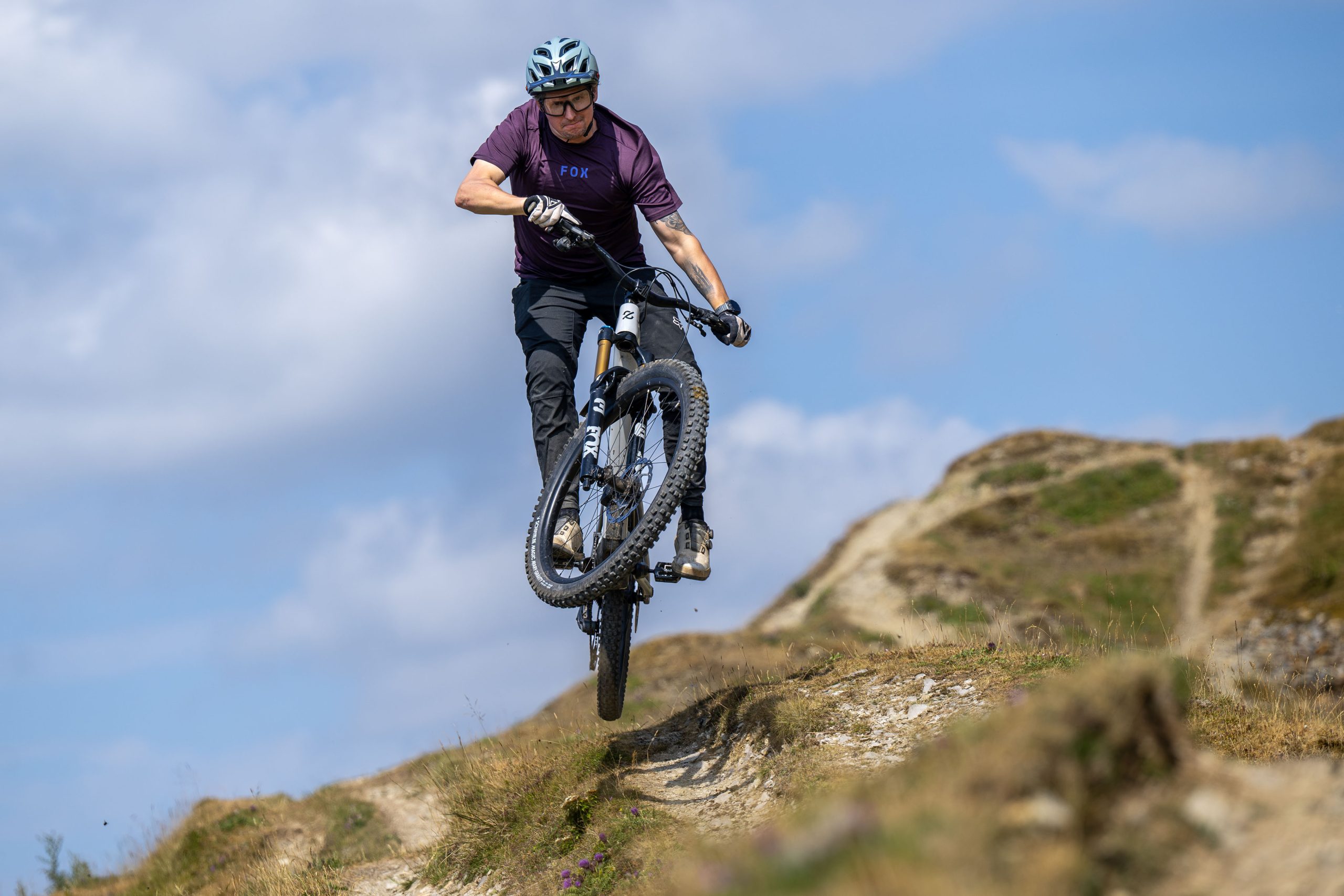 Rider jumping a white Amflow PX Carbon Pro electric mountain bike on a dry mountain trail