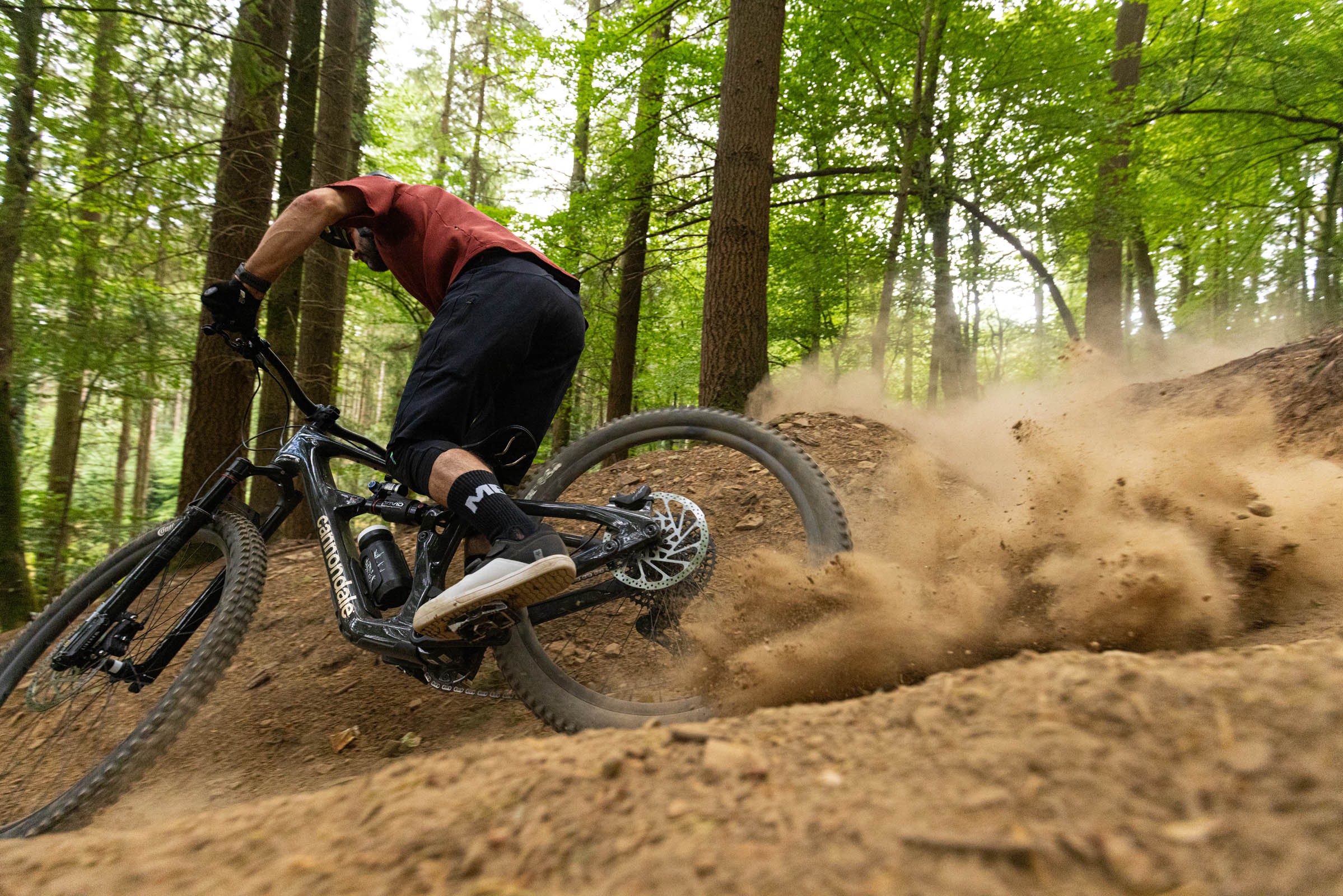 Rider kicking up dust through a righthand turn aboard a Cannondale Bad Habit 1.