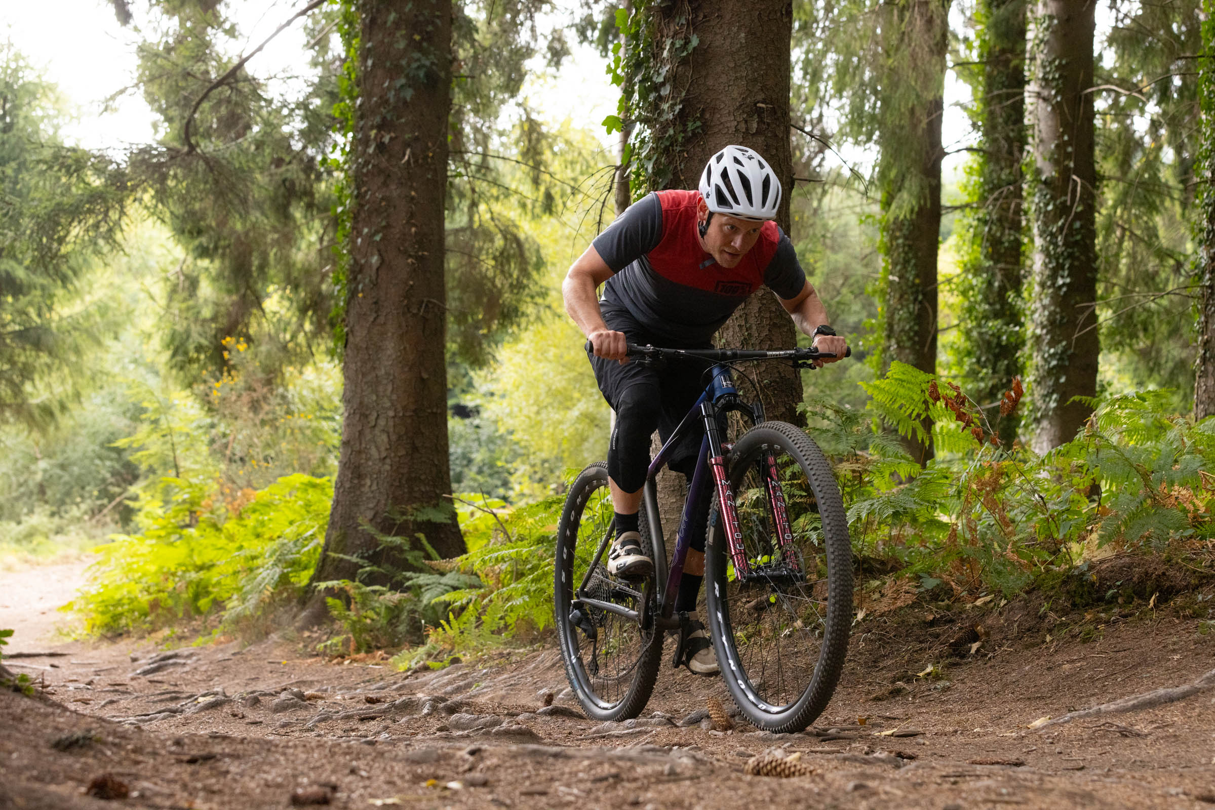 Rider climbibg a wooded trail on the Sour Cycles Pasta Party 32 hardtail mountain bike.