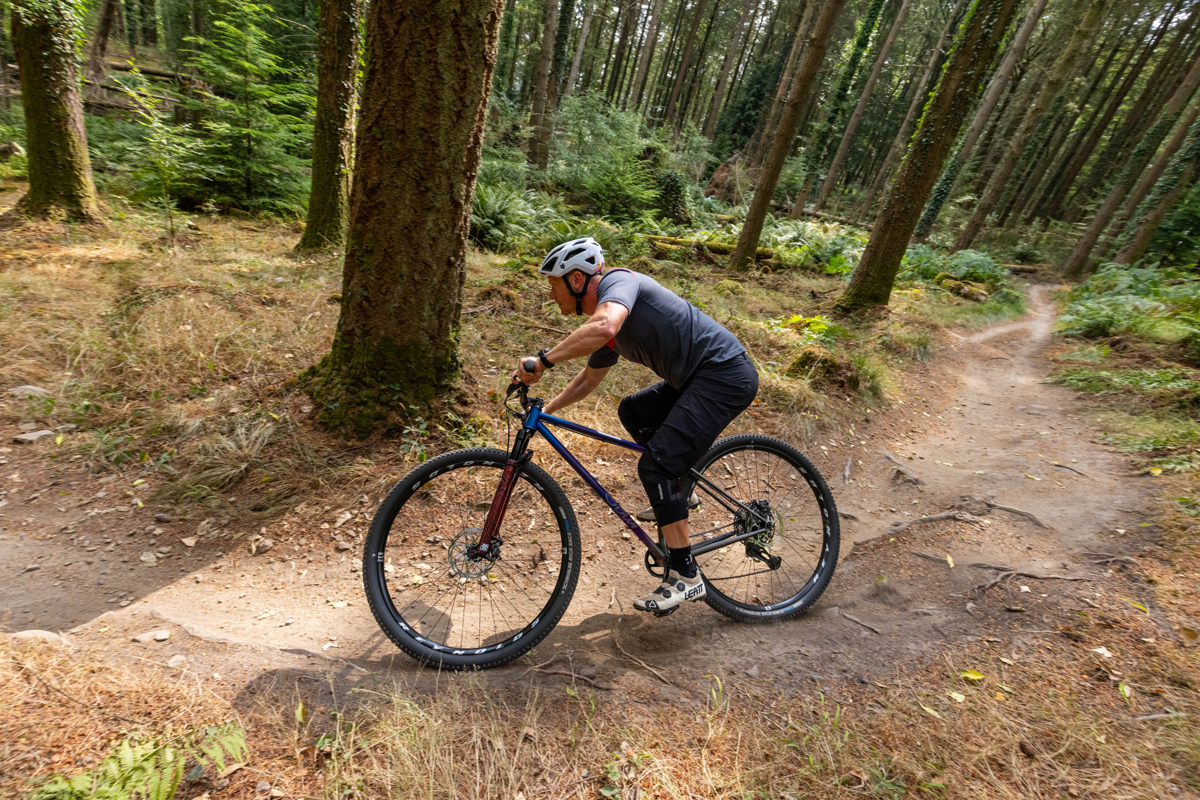 Rider descending a flowing forest trail on the Sour Cycles Pasta Party 32 hardtail mountain bike.