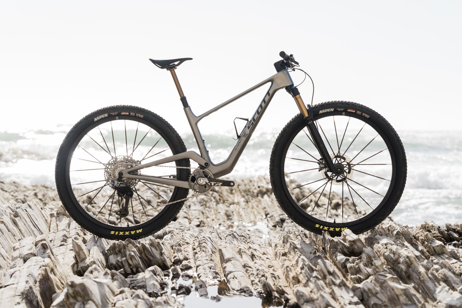 Cross country mountain bike fitted with Cadex Max XC carbon wheels on rocky coastal terrain.