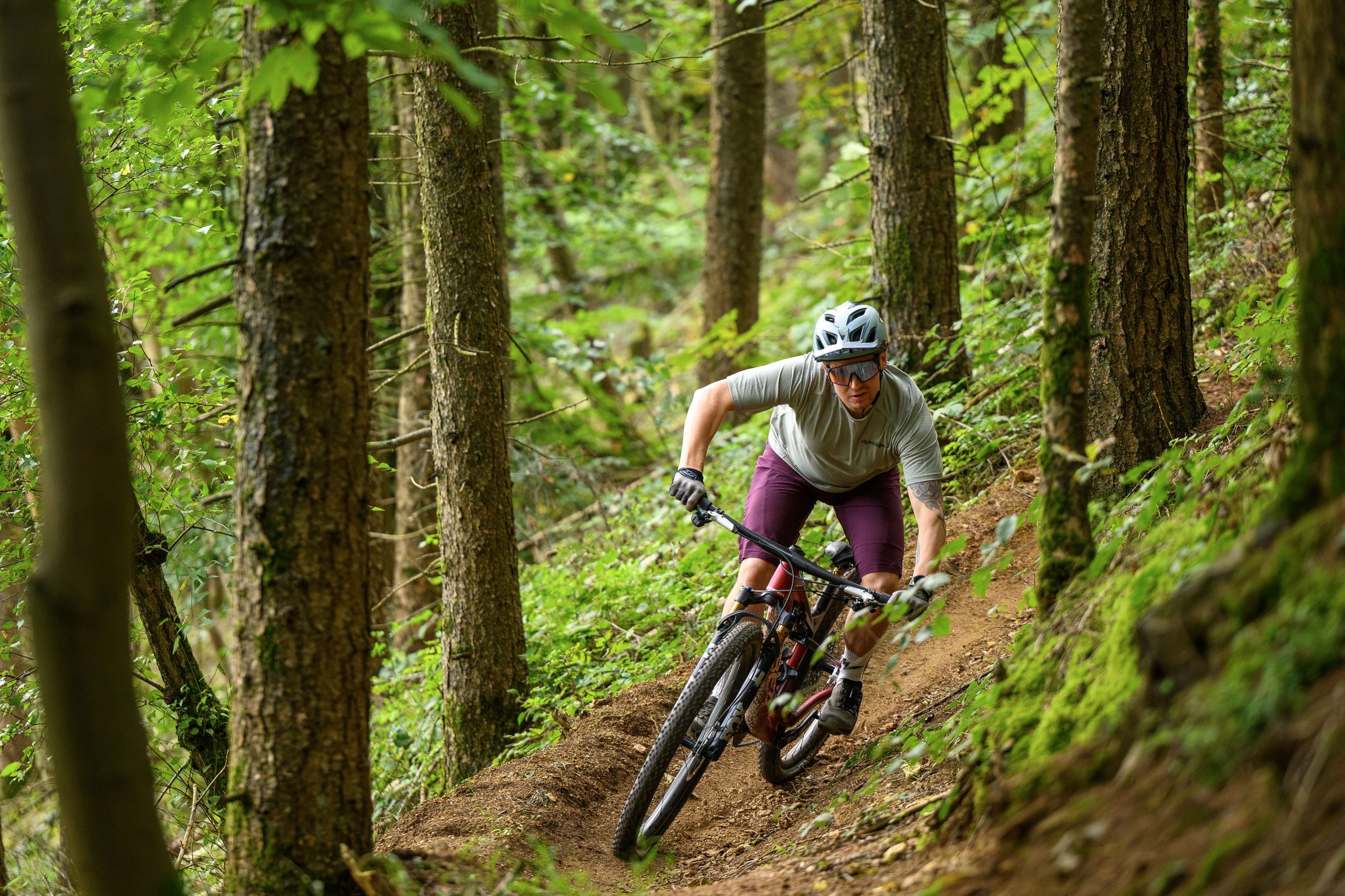 Rider in white t-shirt turning through a singletrack berm aboard the Orbea Oiz.