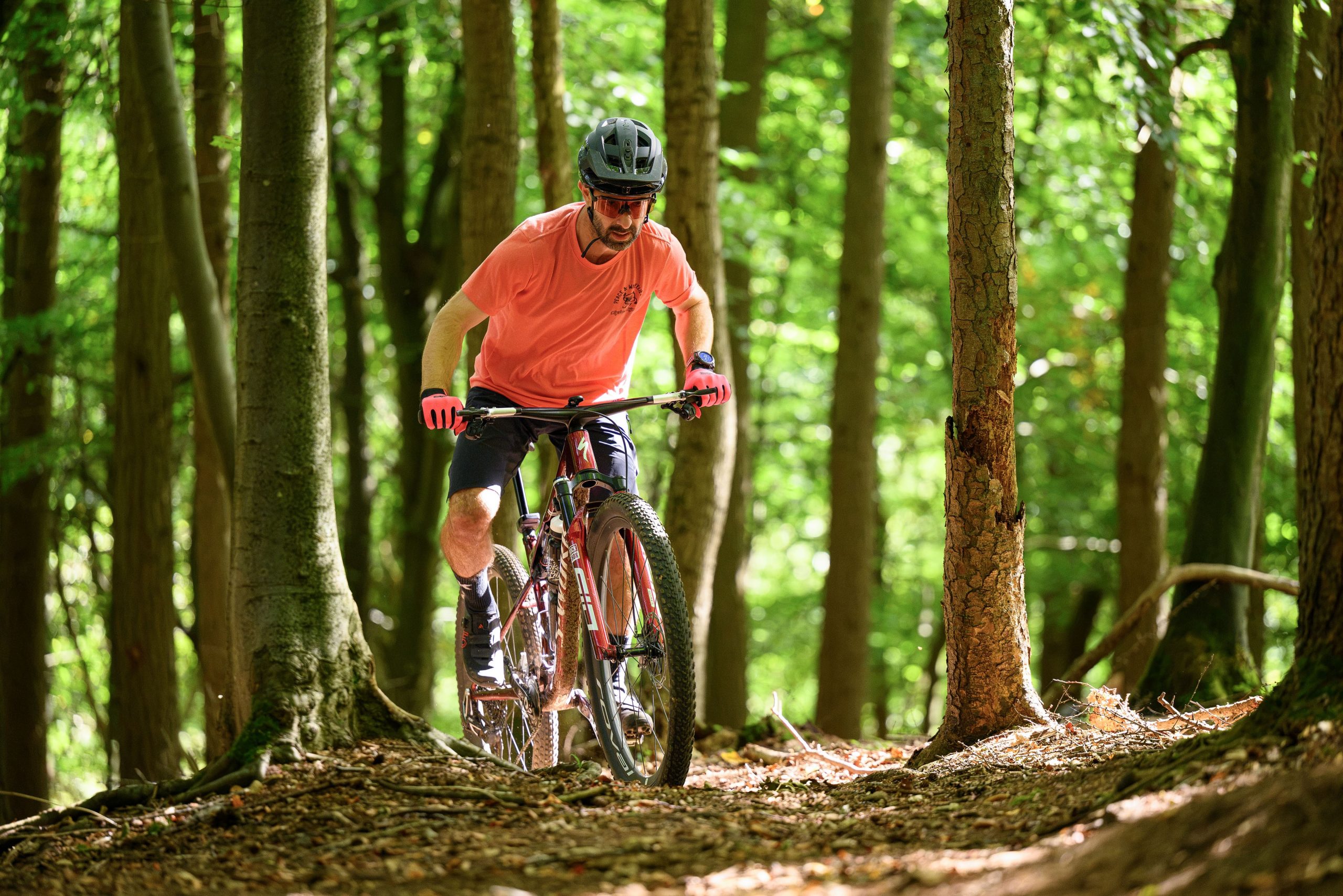 Rider in red t-shirt riding the Specialized Epic 9 tackling tricky climb.