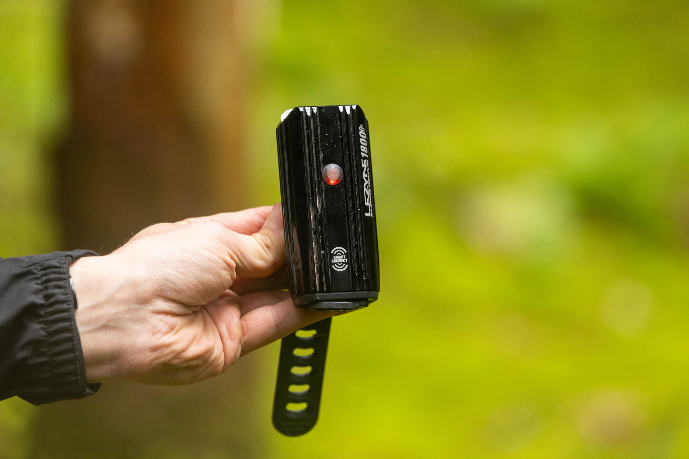Lezyne Super Drive 1800+ Smart front light held in a hand with its red battery indicator illuminated.