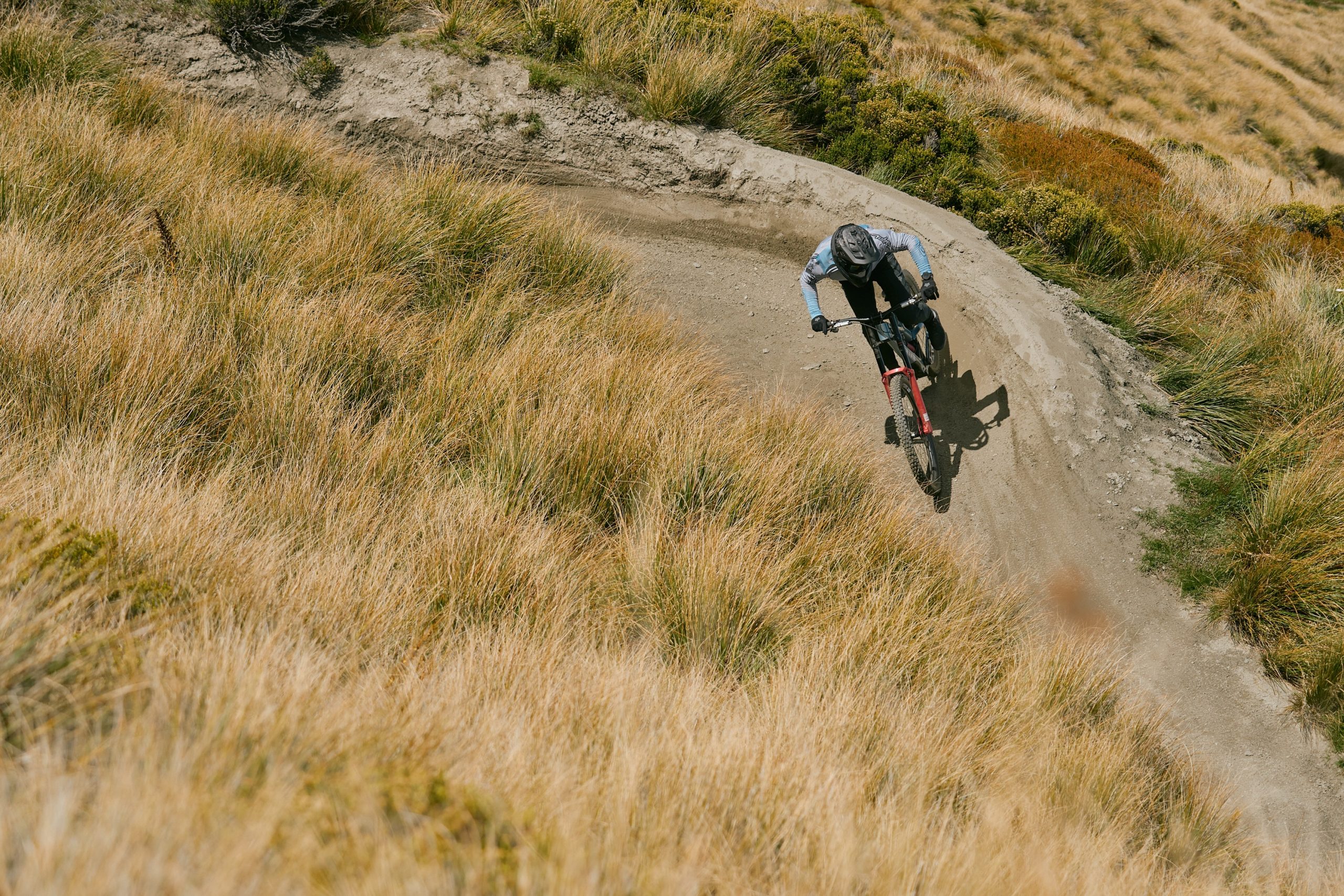 Riding cornering on berm part way down the Coronet Peak DH track in New Zealand and riding RockShox Boxxer.