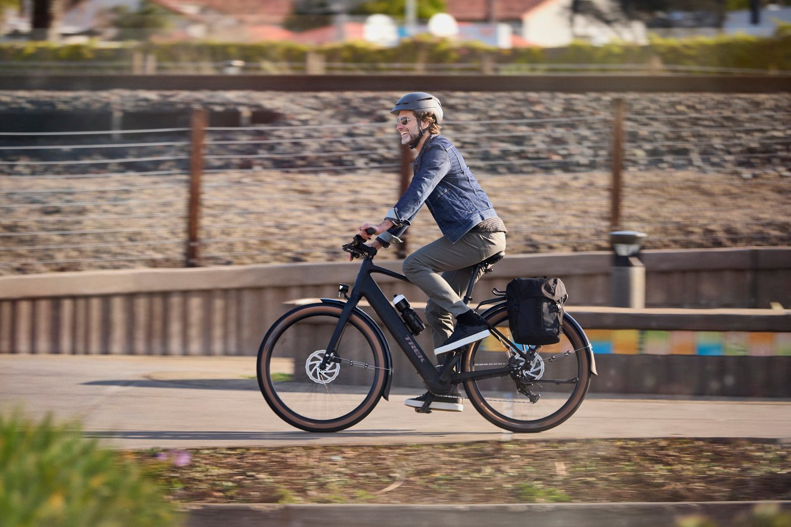 Man riding Trek FX+1 electric bike with panniers.