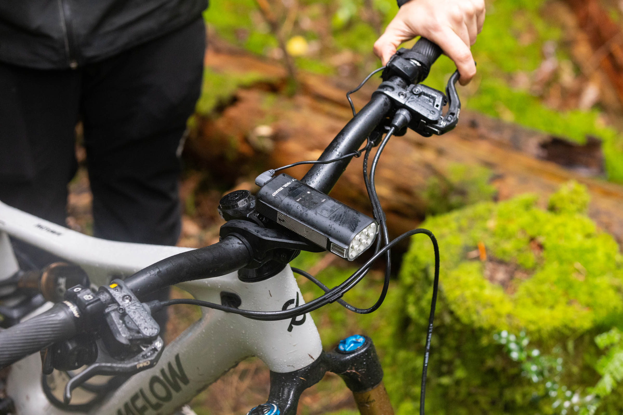 Moon Rigel Enduro 2600 front light mounted on a mountain bike handlebar with its wired remote control near the right-hand grip.