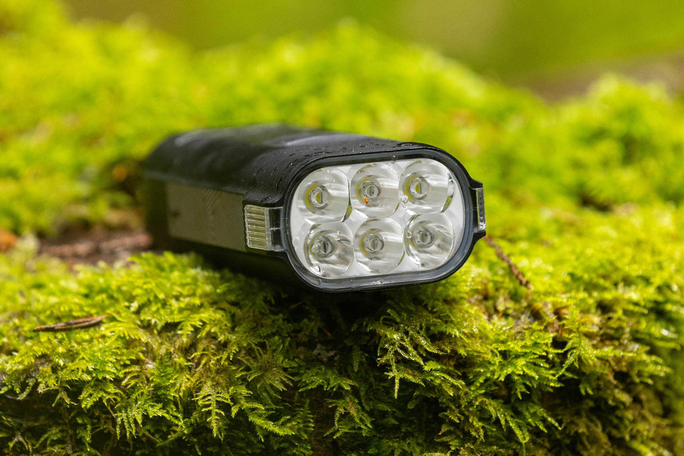 Close-up of the six-LED lens on a Moon Rigel Enduro 2600 mountain bike front light resting on moss.