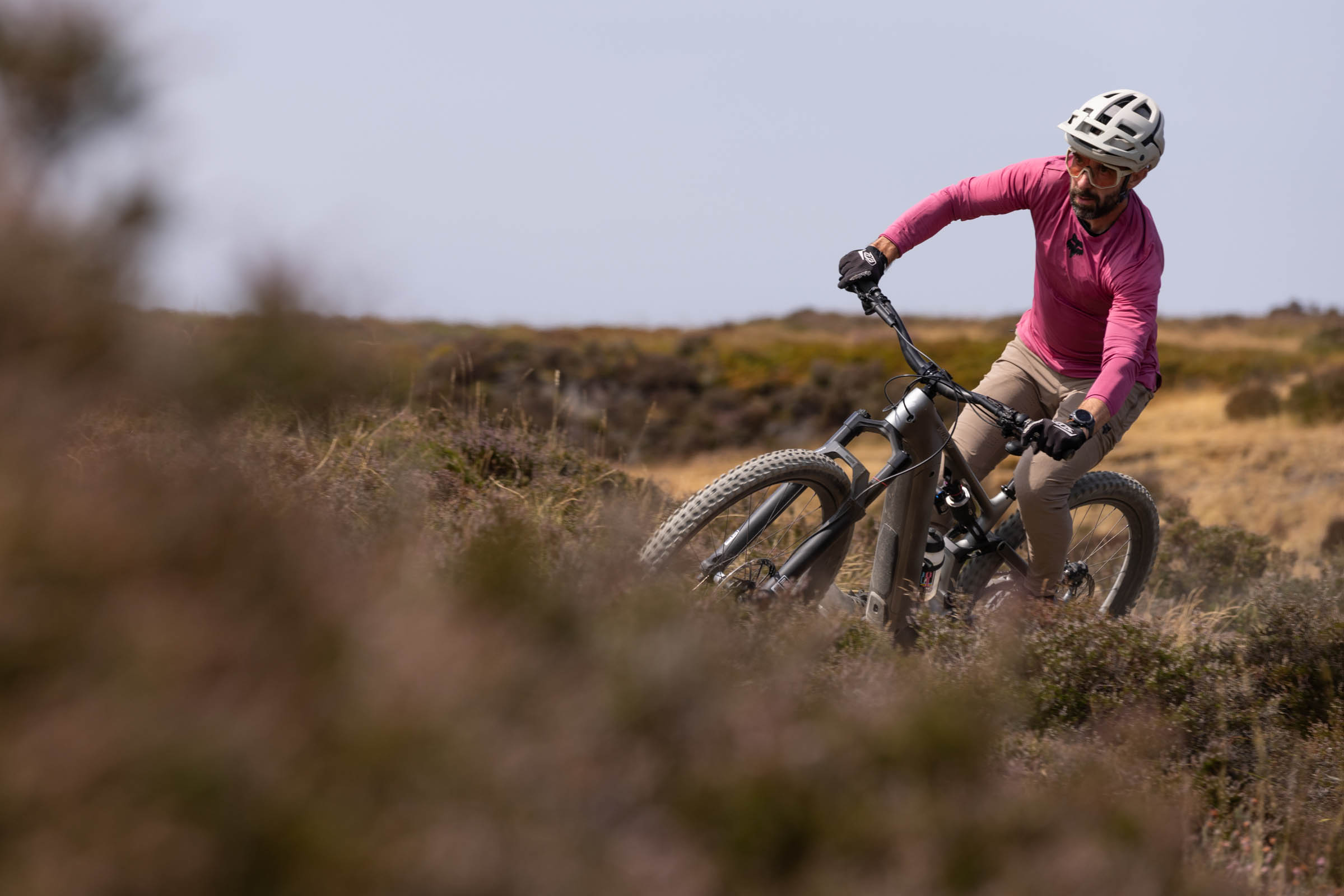 Rider cornering on a silver Specialized Levo 4 EVO Pro electric mountain bike across open moorland