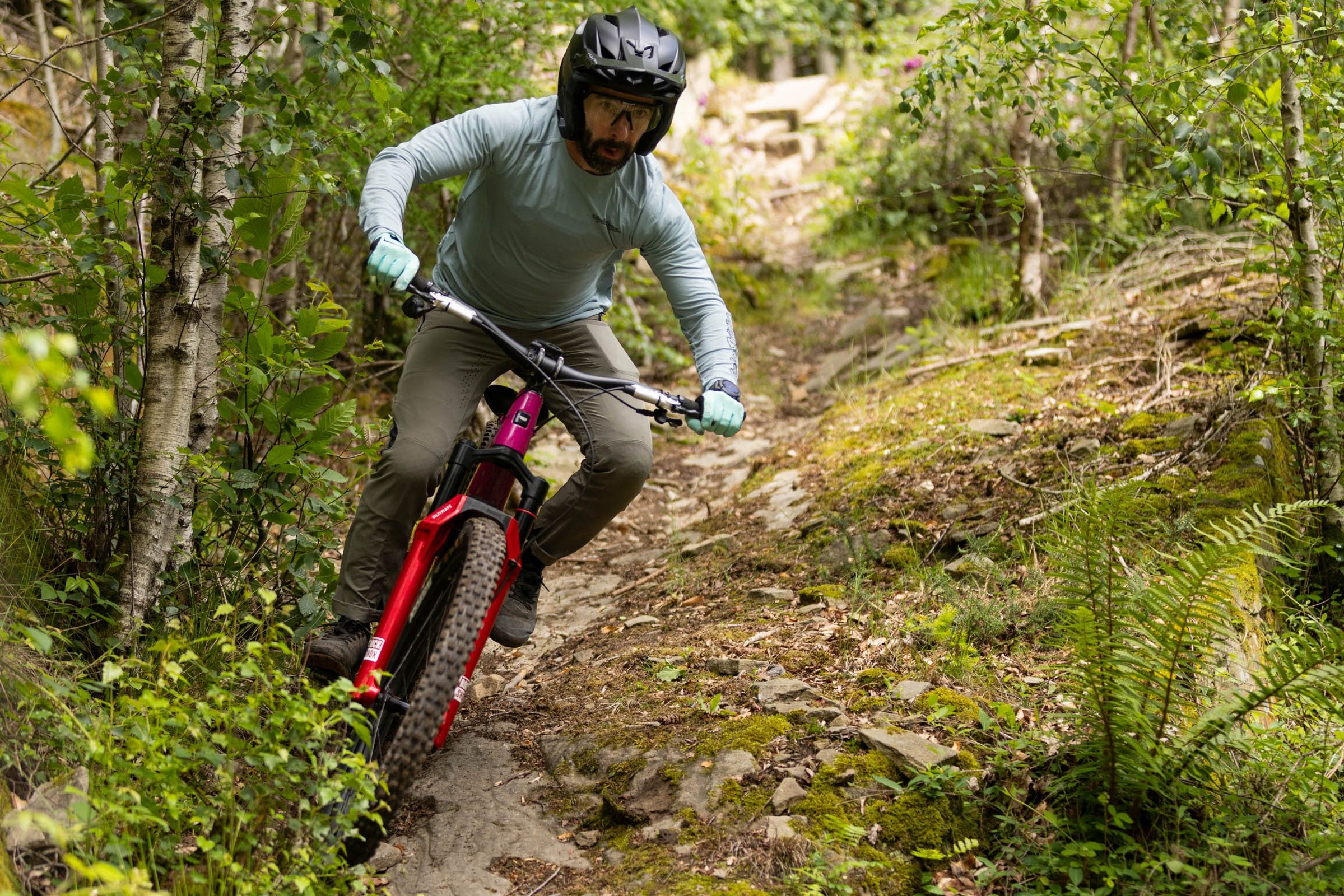 Rider descending down a rocky gully surrounded by trees and riding a Santa Cruz Bronson with RockShox ZEB Ultimate fork.