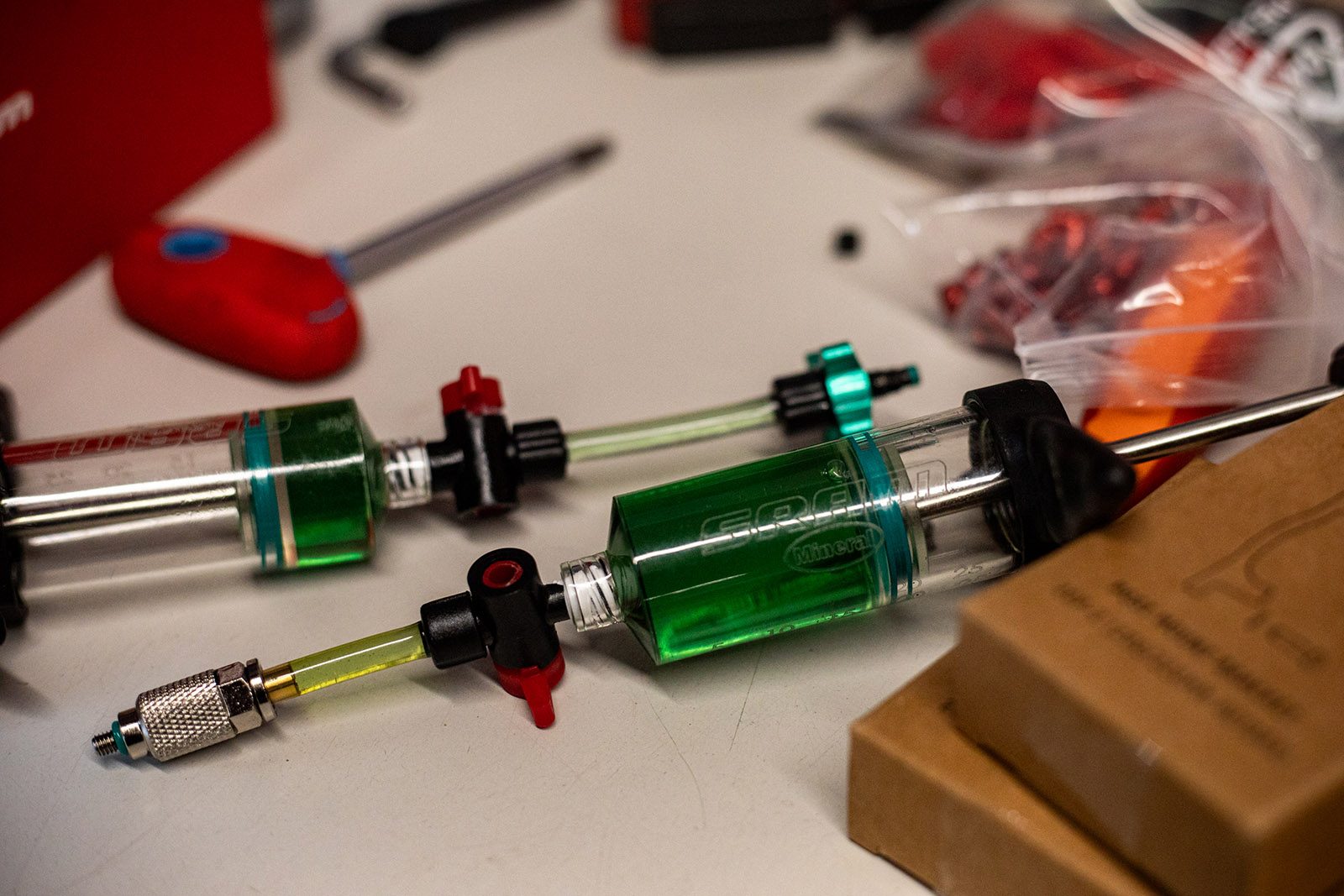 SRAM Maven bleed kit pictured with syringes partially filled with green mineral oil and surrounded by tools.