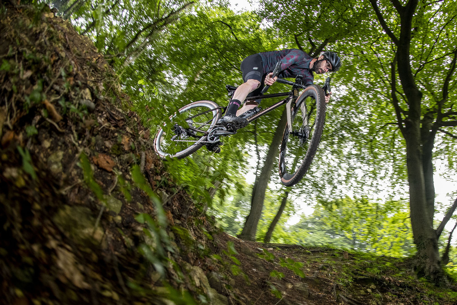 Male cyclist riding the Rå Valravn S gravel bike through woodland