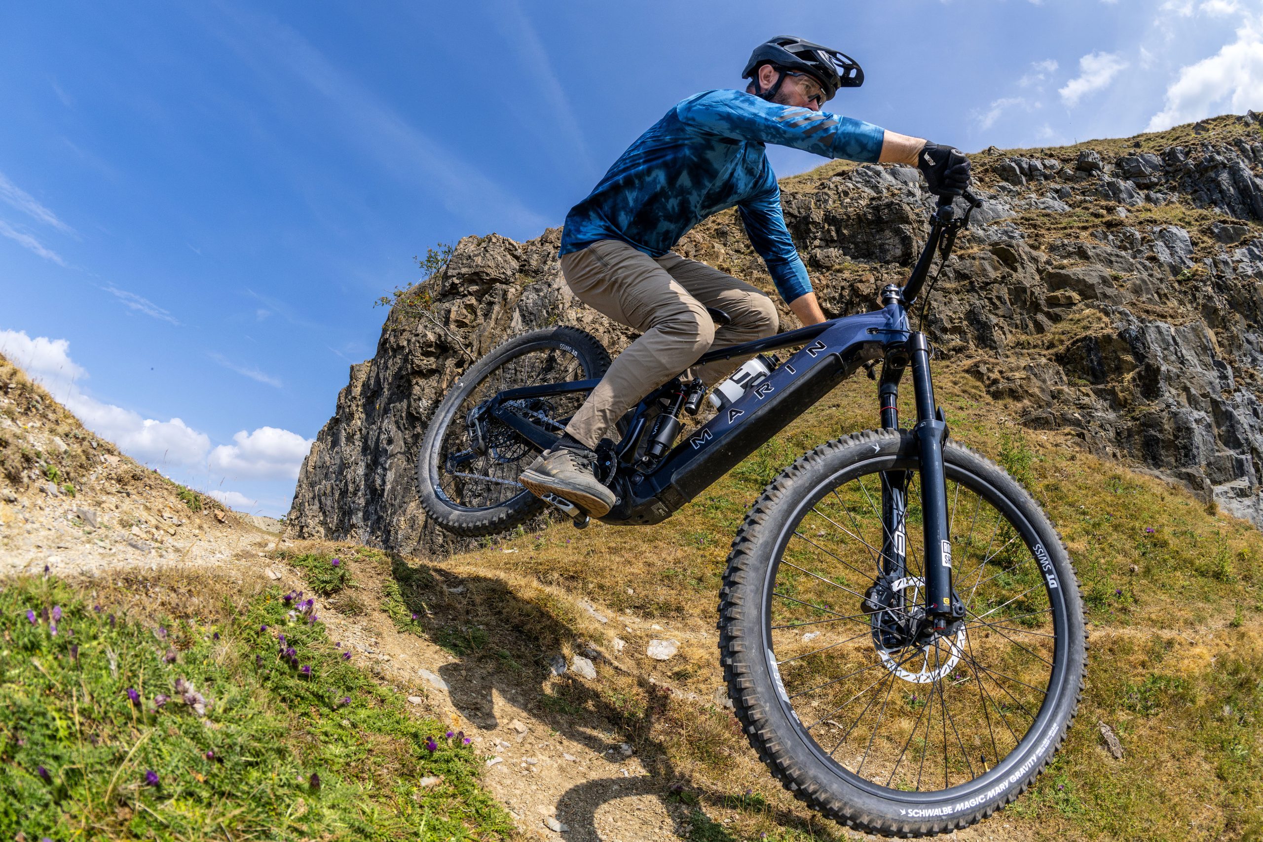 Rider drops the dark blue Marin Alpine Trail E XR into a steep, rocky trail section