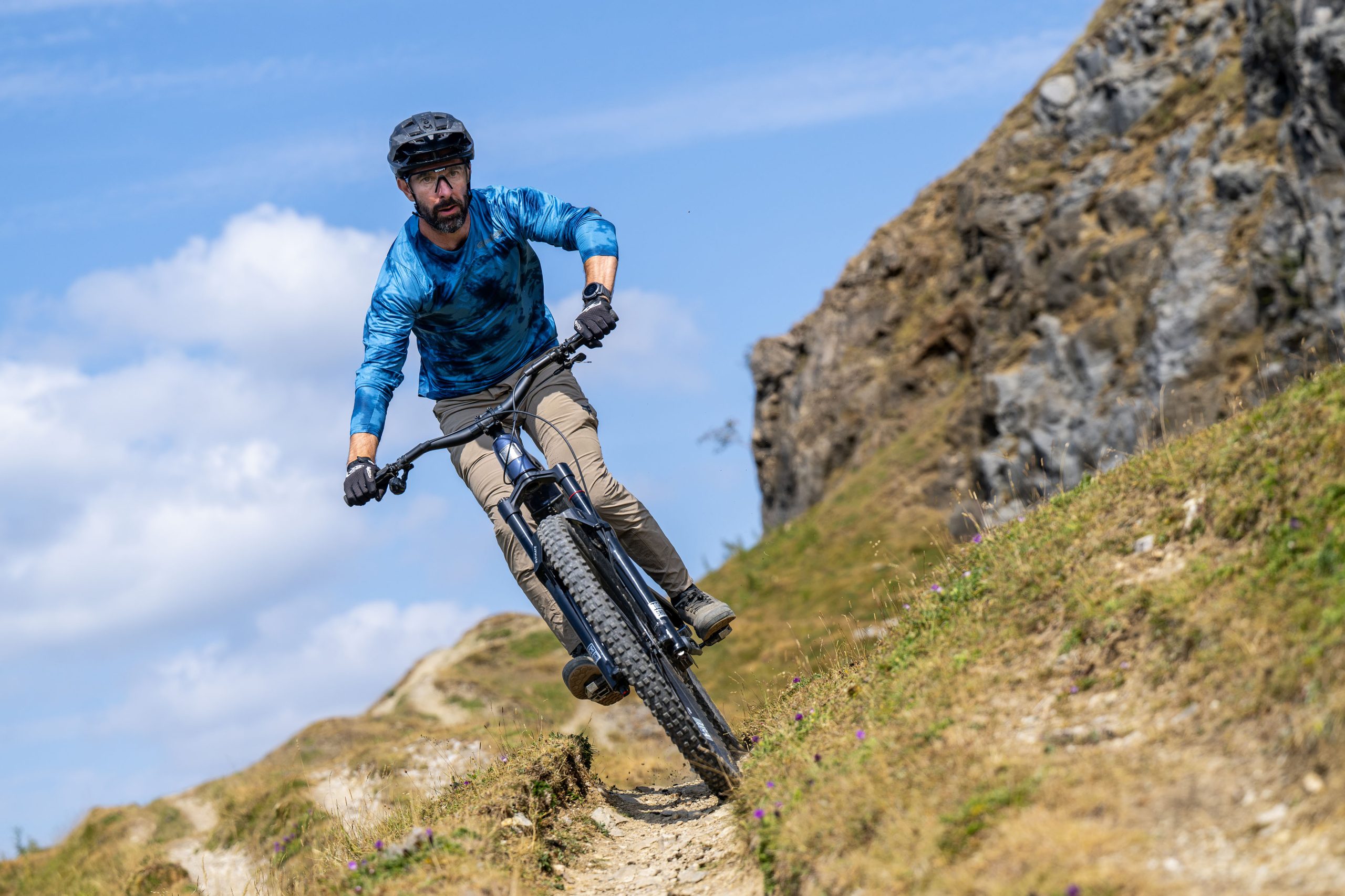 Rider corners the dark blue Marin Alpine Trail E XR on a fast, rocky mountainside trail