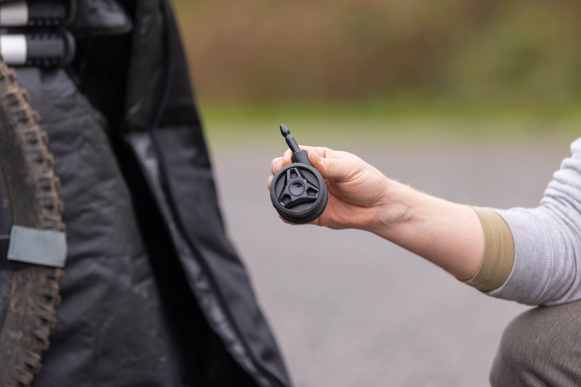 Close-up of a person holding the removable front caster wheel from the Thule RoundTrip MTB travel case.
