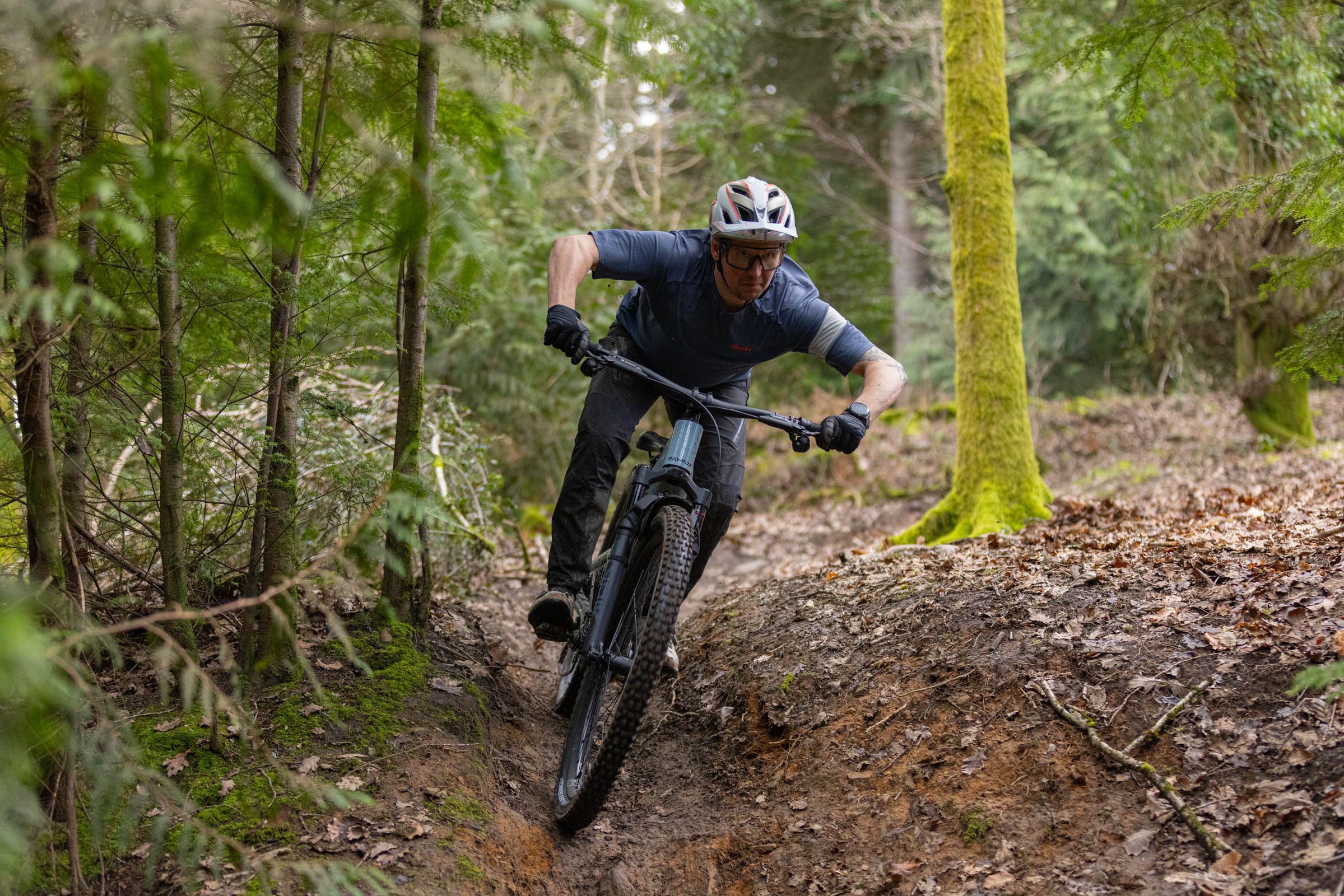 Rider leaning the Raymon Ravor Ultra e-MTB through a rutted woodland corner