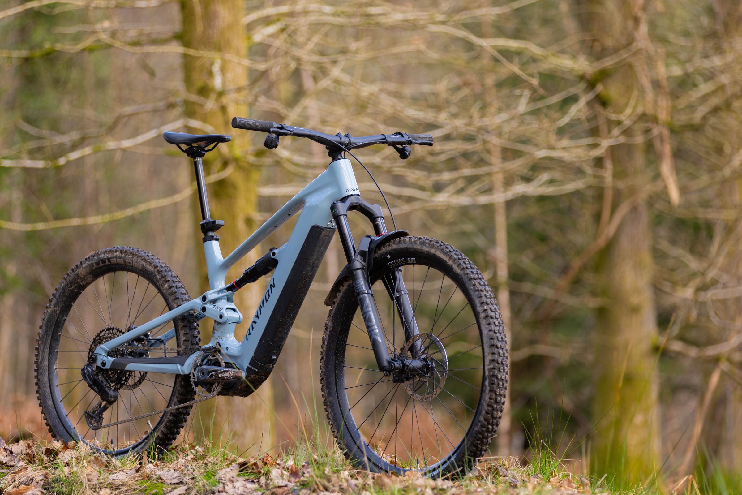 Three-quarter view of the Raymon Ravor Ultra electric mountain bike standing in woodland