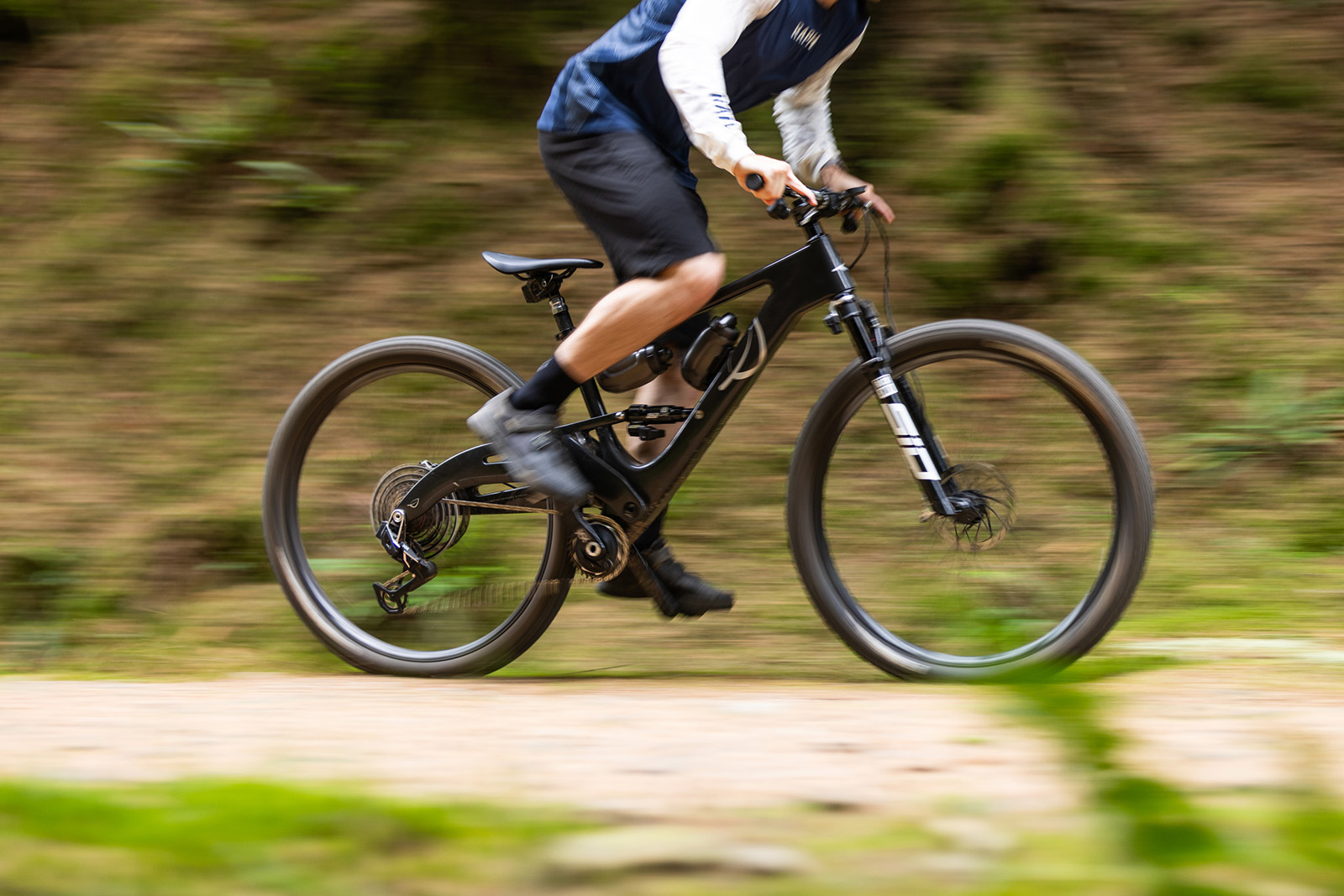 Male rider in blue and white top riding the Lauf Elja XC Ultimate Flight Attendant full suspension mountain bike