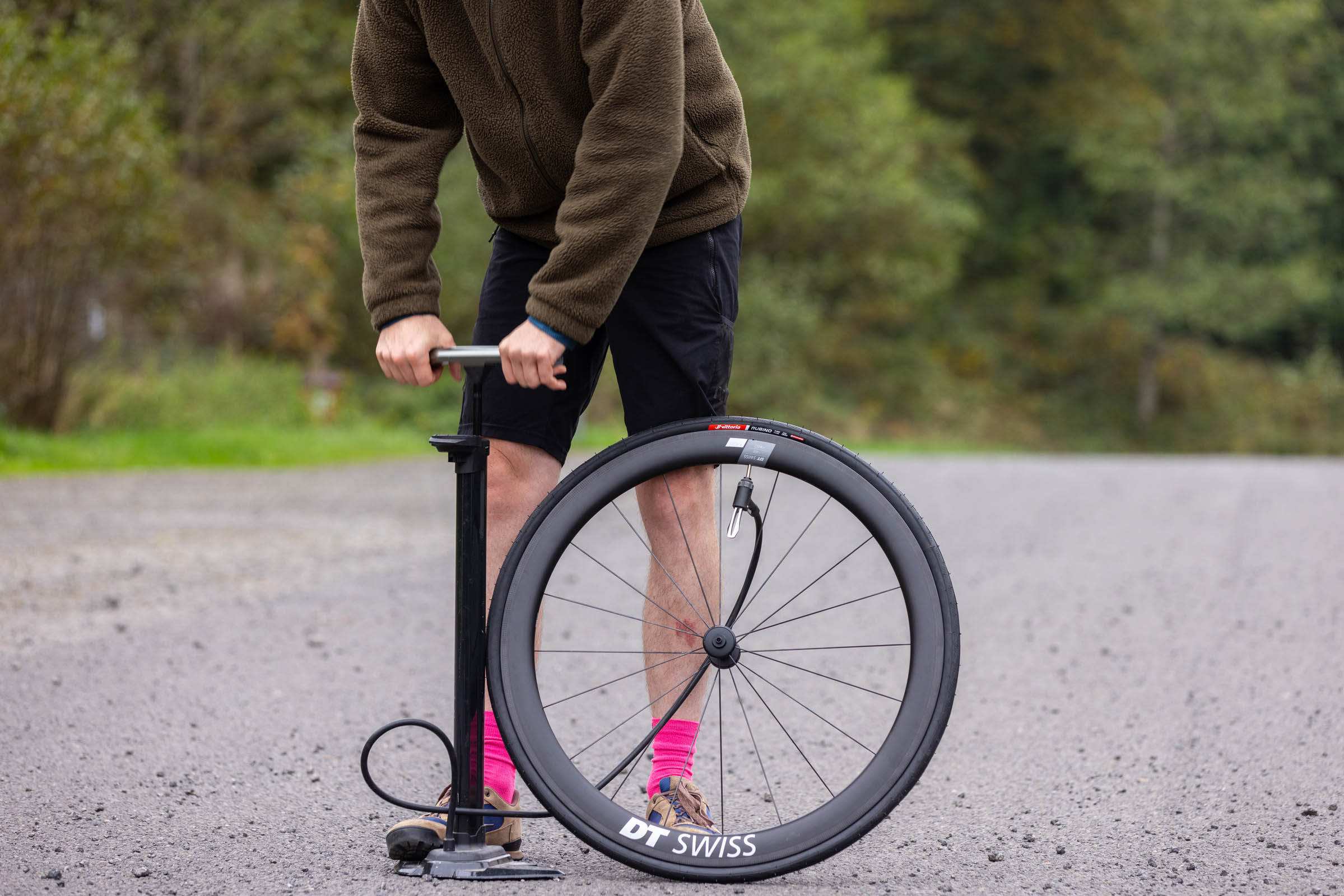 Person using a track pump to inflate Vittoria tyre on DT Swiss road bike wheel