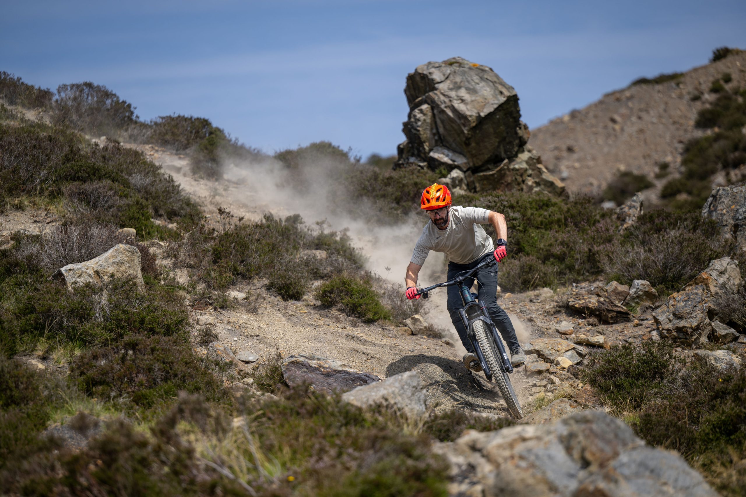 Rider descends a loose, rocky trail on the dark green Merida Lithos 8000 eMTB