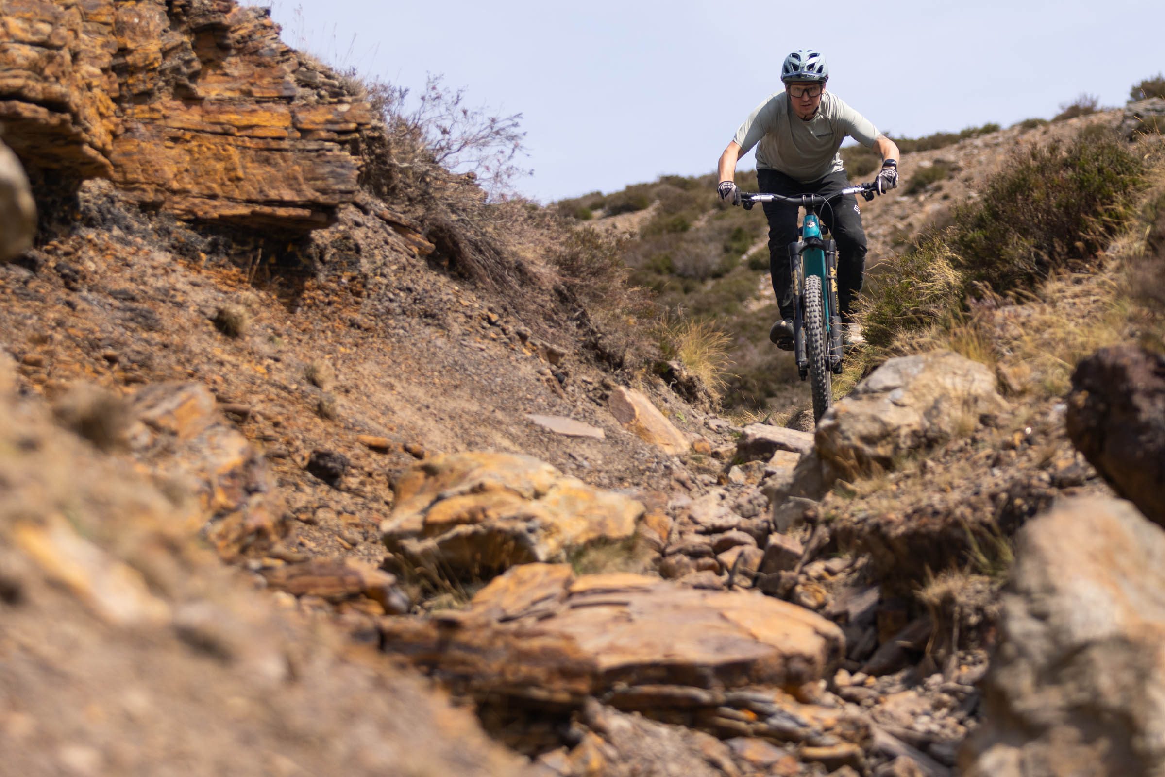 Rider descending a steep, rocky trail on the turquoise Yeti LTe T4 electric mountain bike.