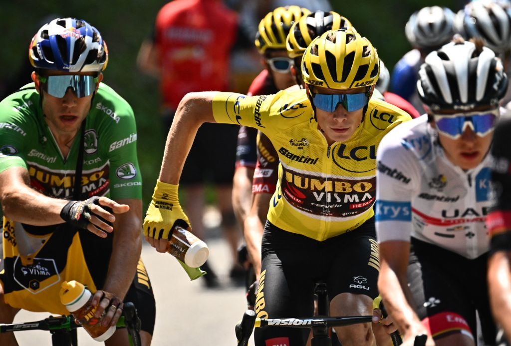 Jumbo-Visma team's Belgian rider Wout Van Aert wearing the sprinter's green jersey (L) hands a water bottle to Jumbo-Visma team's Danish rider Jonas Vingegaard wearing the overall leader's yellow jersey (C) as they cycle behind UAE Team Emirates team's Slovenian rider Tadej Pogacar wearing the best young rider's white jersey (R) in the ascent of Hourquette d'Ancizan during the 17th stage of the 109th edition of the Tour de France cycling race, 129,7 km between Saint-Gaudens and Peyragudes in southwestern France, on July 20, 2022. (Photo by Marco BERTORELLO / AFP) (Photo by MARCO BERTORELLO/AFP via Getty Images)