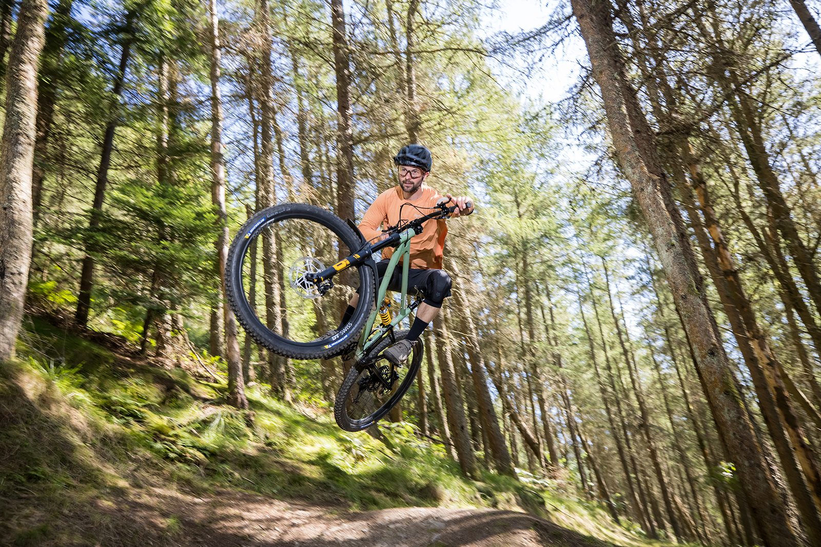 Male rider (Alex Evans) in orange top riding the Starling Murmur full suspension mountain bike