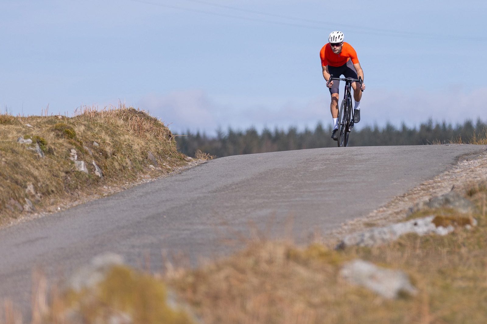 Male cyyclist in orange top riding the Orbea Orca M20i Team road bike